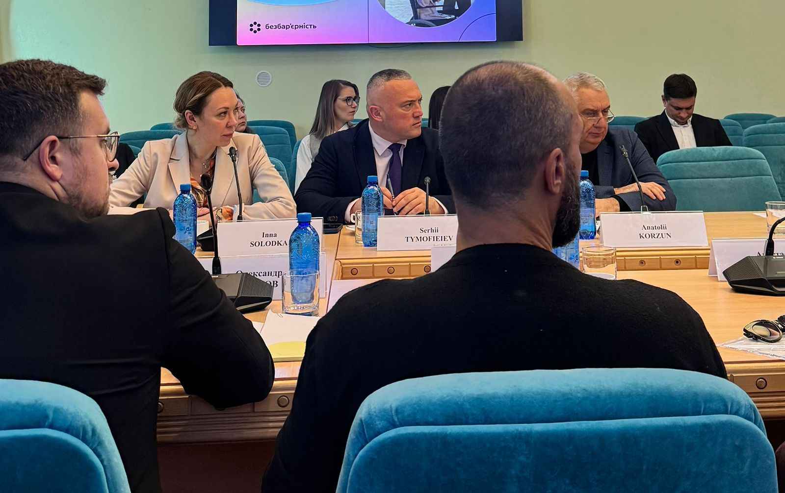 На фото жінки та чоловіки сидять за столом під час зустрічі