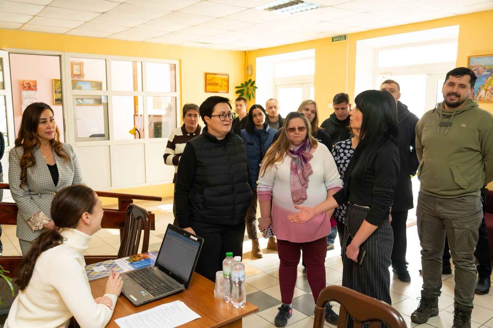 На фото жінки та чоловіки спілкуються у приміщенні