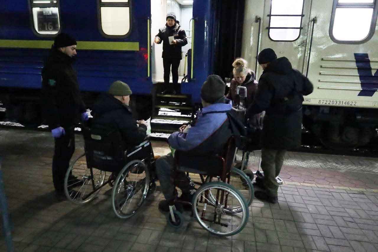 Дві людини на візку на фоні поїзду