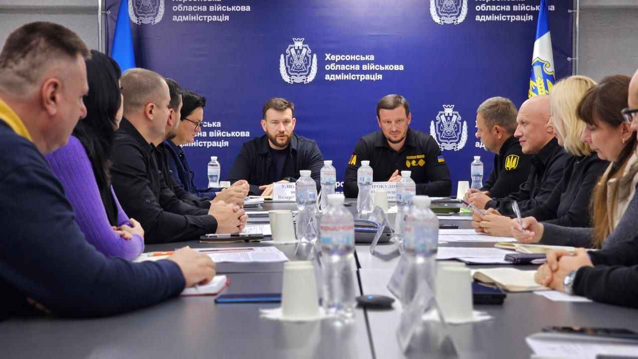 На фото зображено чоловіків та жінок, які сидять за столом під час наради