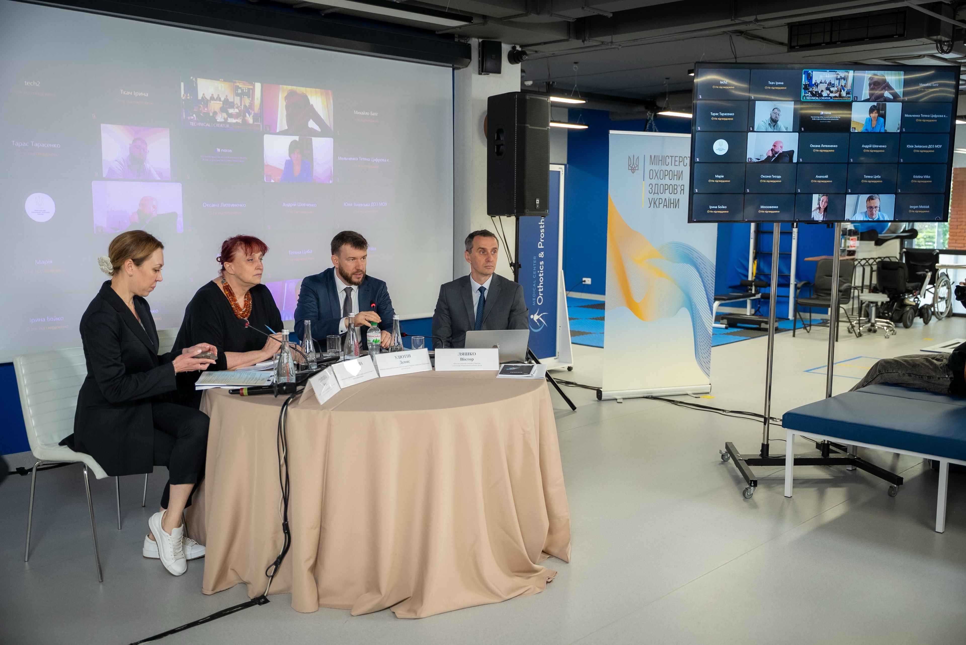 На фото жінки та чоловіки сидять в президії під час заходу