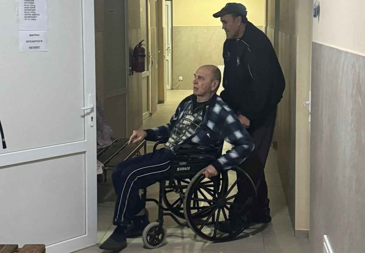 Чоловік везе особу з інвалідністю на візку у приміщенні