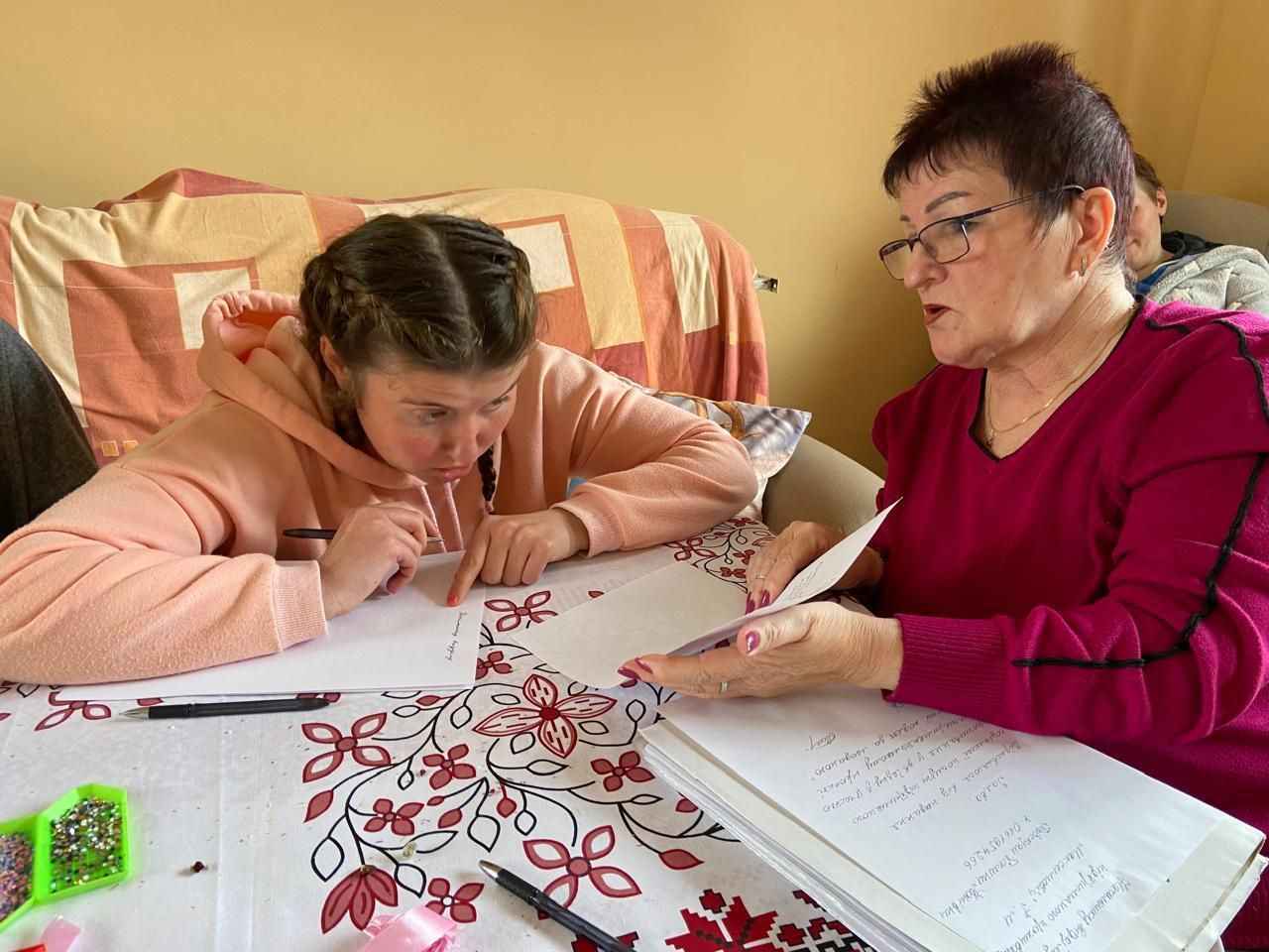 На фото дитина та жінка сидять за столом