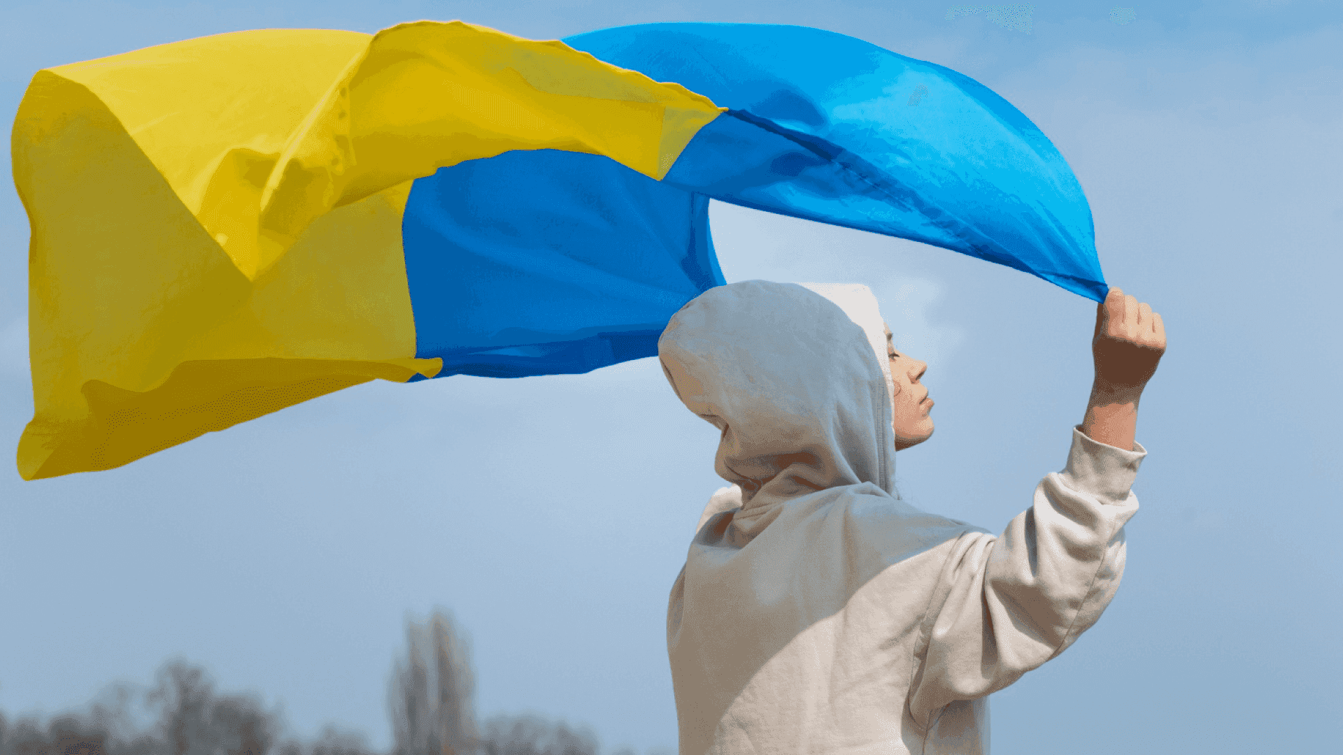 На фото зображено хлопця, який тримає над собою прапор України 