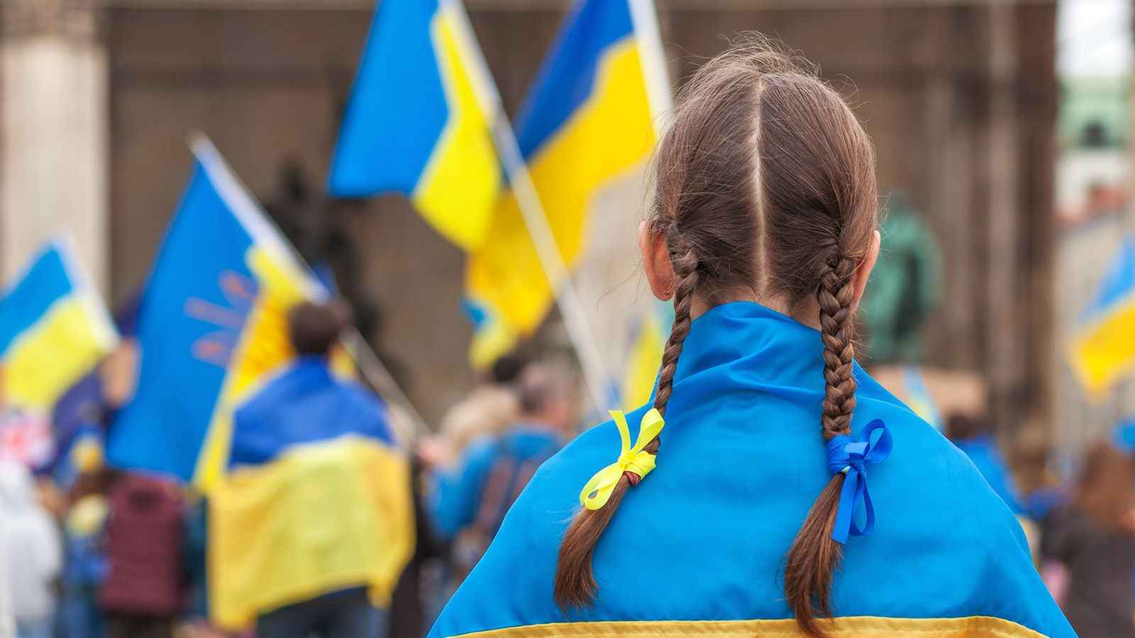 На фото зображено дівчину на фоні жовто-блакитних прапорів