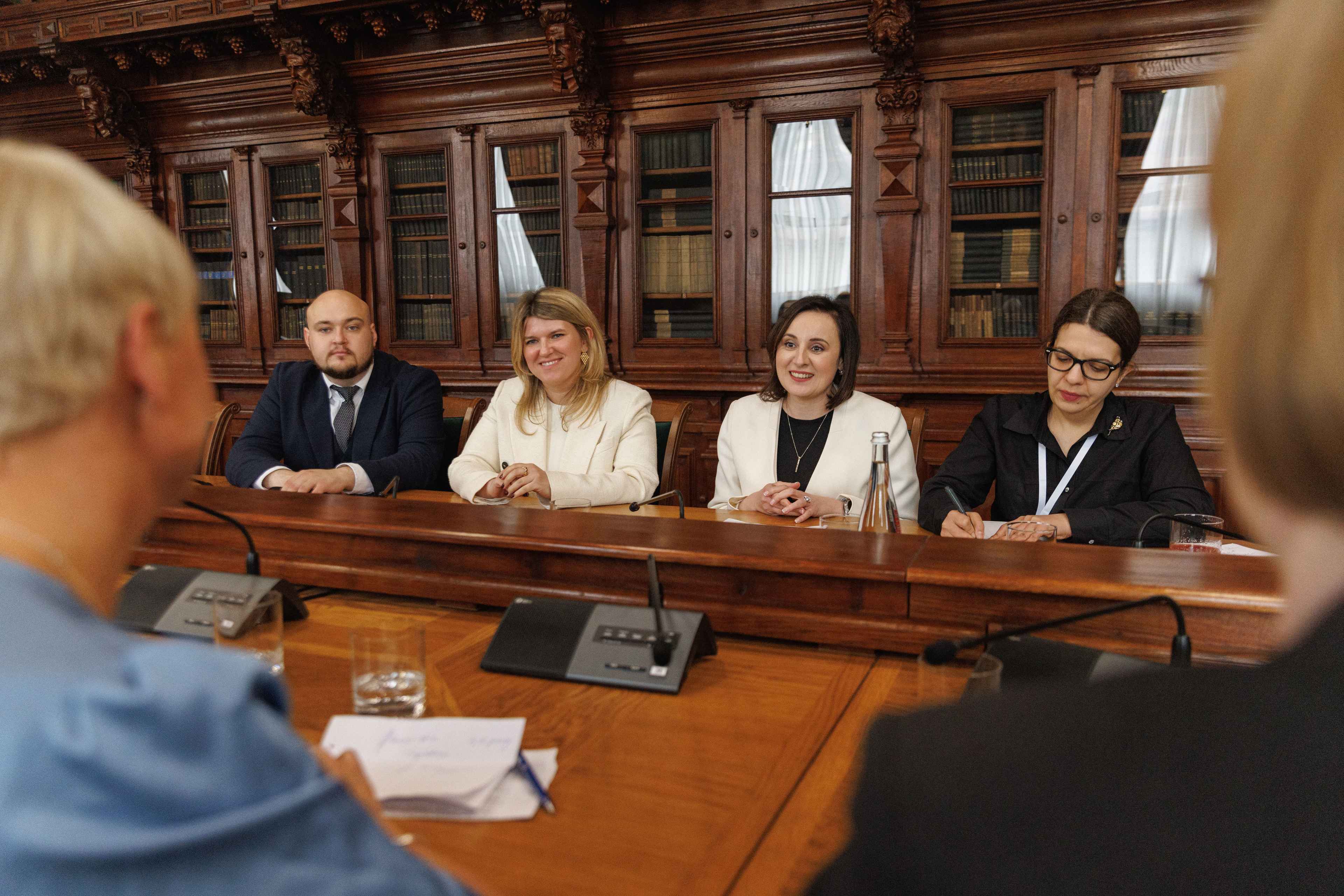 На фото жінки і чоловік сидять за столом