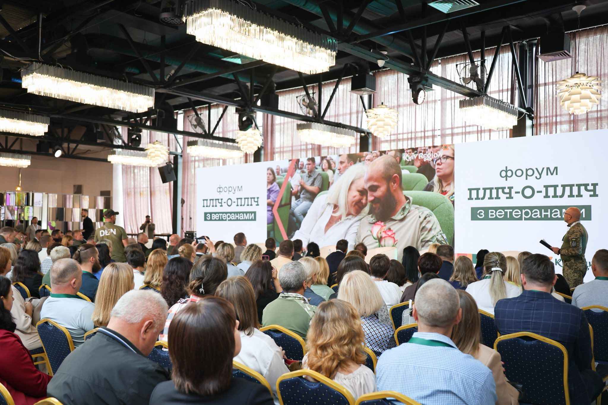 На фото чоловіки та жінки сидять у залі під час заходу