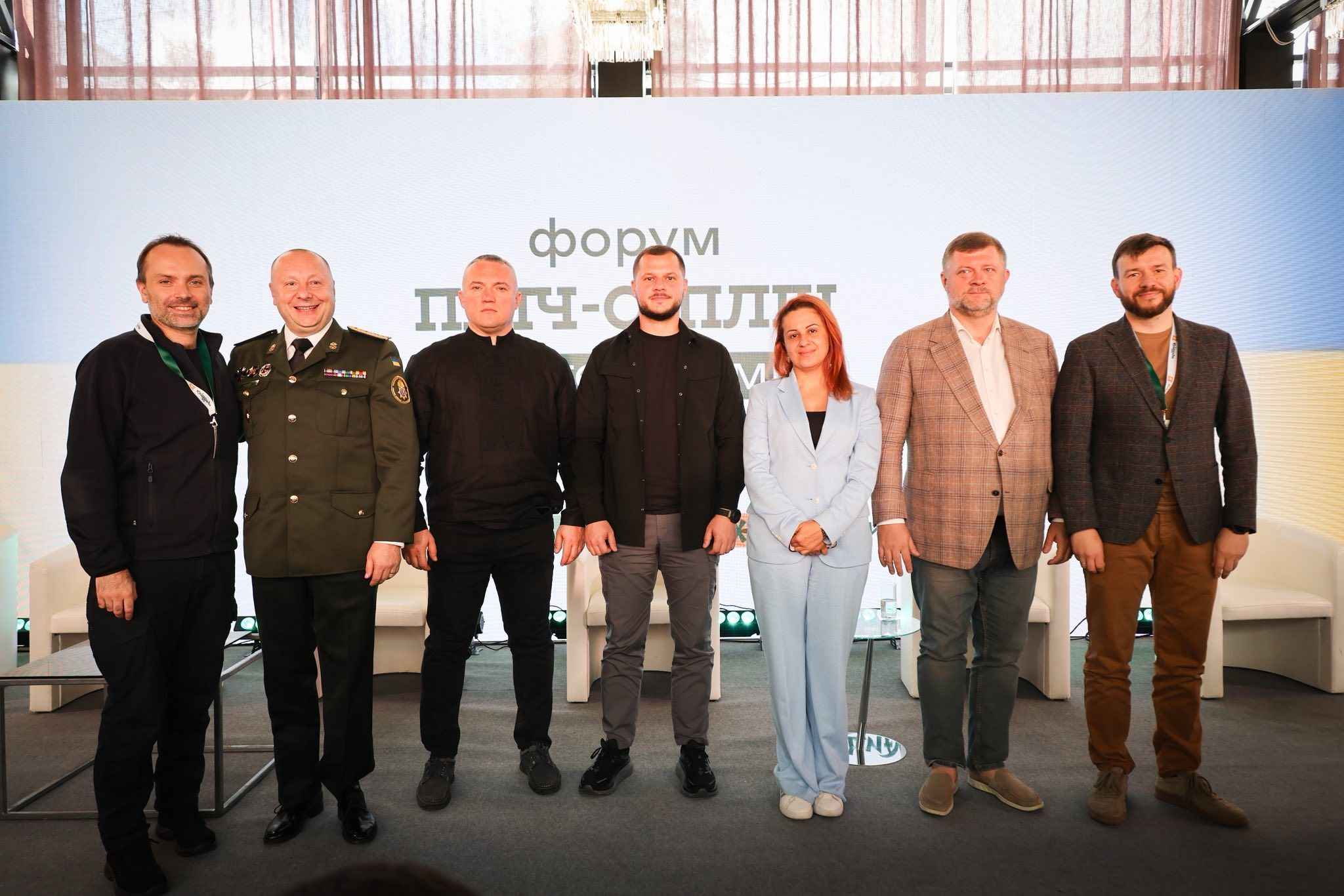 На фото чоловіки та жінка на фоні сцени після заходу
