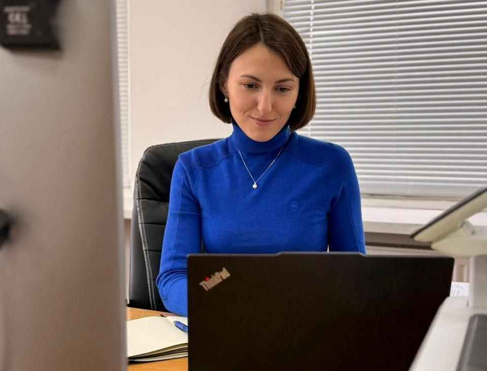 На фото жінка дивиться в екран ноутбука під час онлайн наради