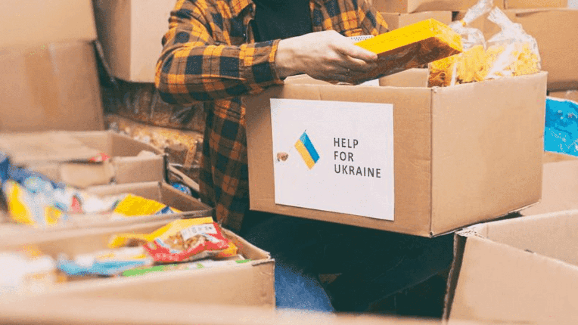 На фото людина тримає в руках коробку з речами