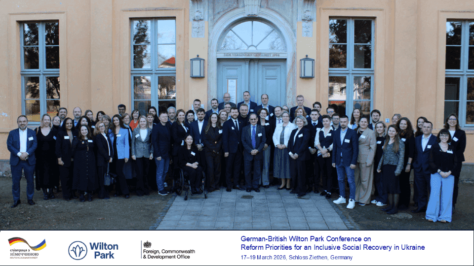 На фото чоловіки та жінки стоять на вулиці на фоні будинку