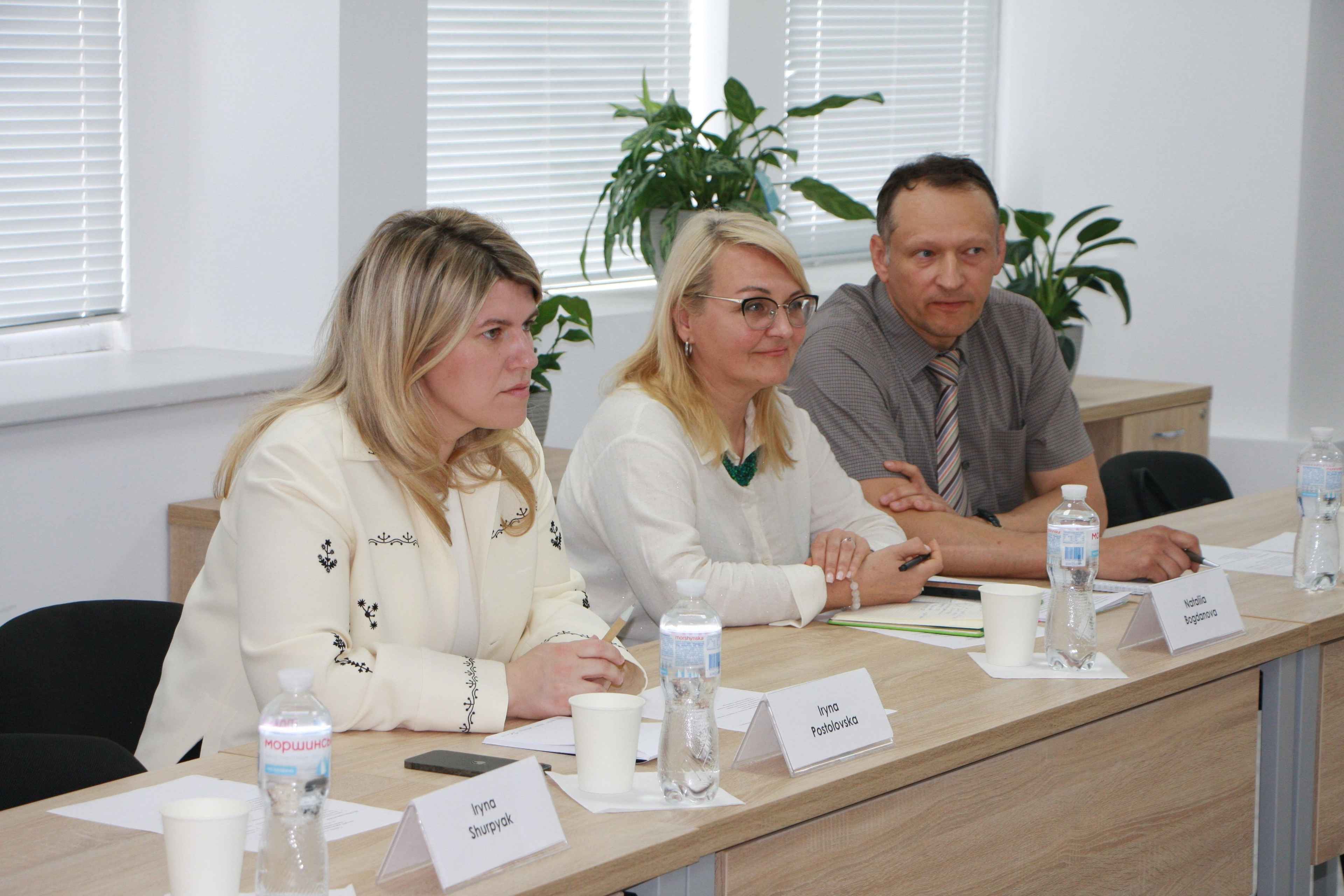 На фото жінки та чоловік сидять за столом