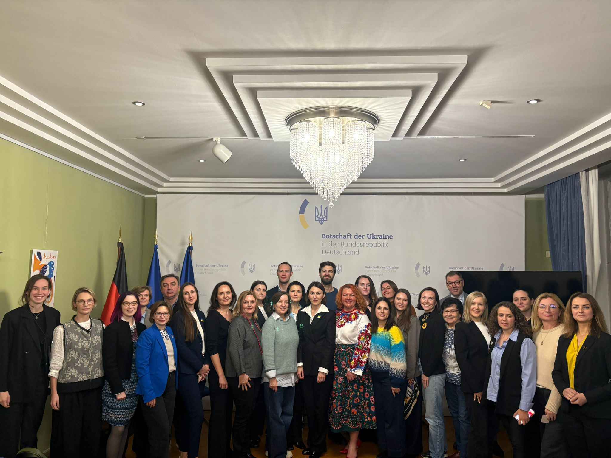 На фото жінки та чоловіки стоять у приміщенні після заходу