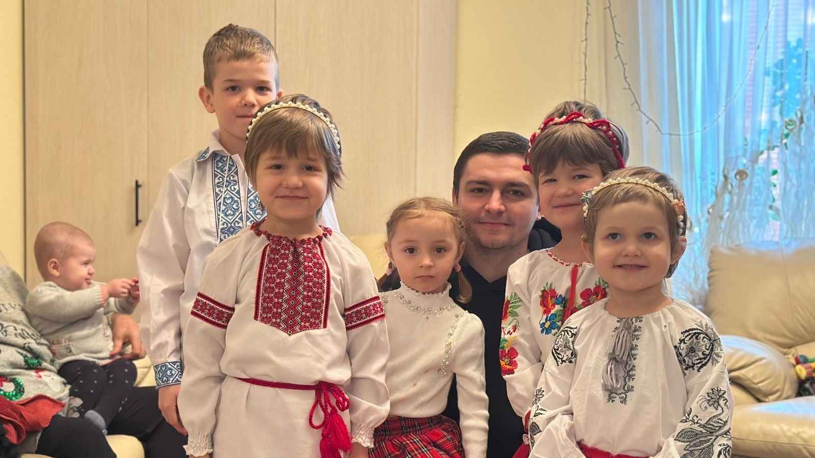 На фото чоловік та діти у вишиванках у кімнаті