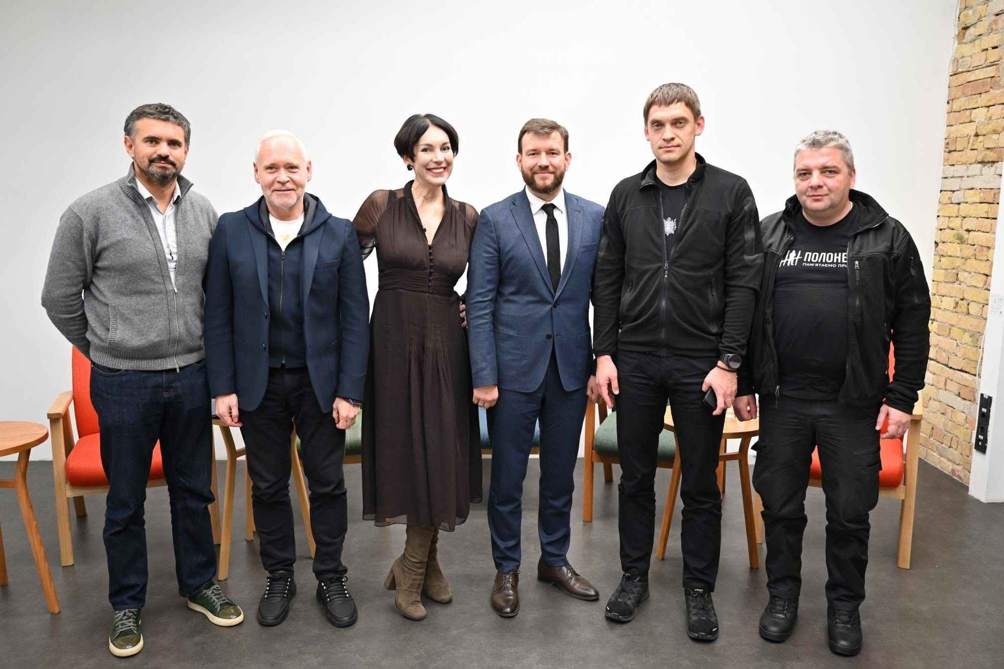 На фото чоловіки та жінка стоять у приміщенні