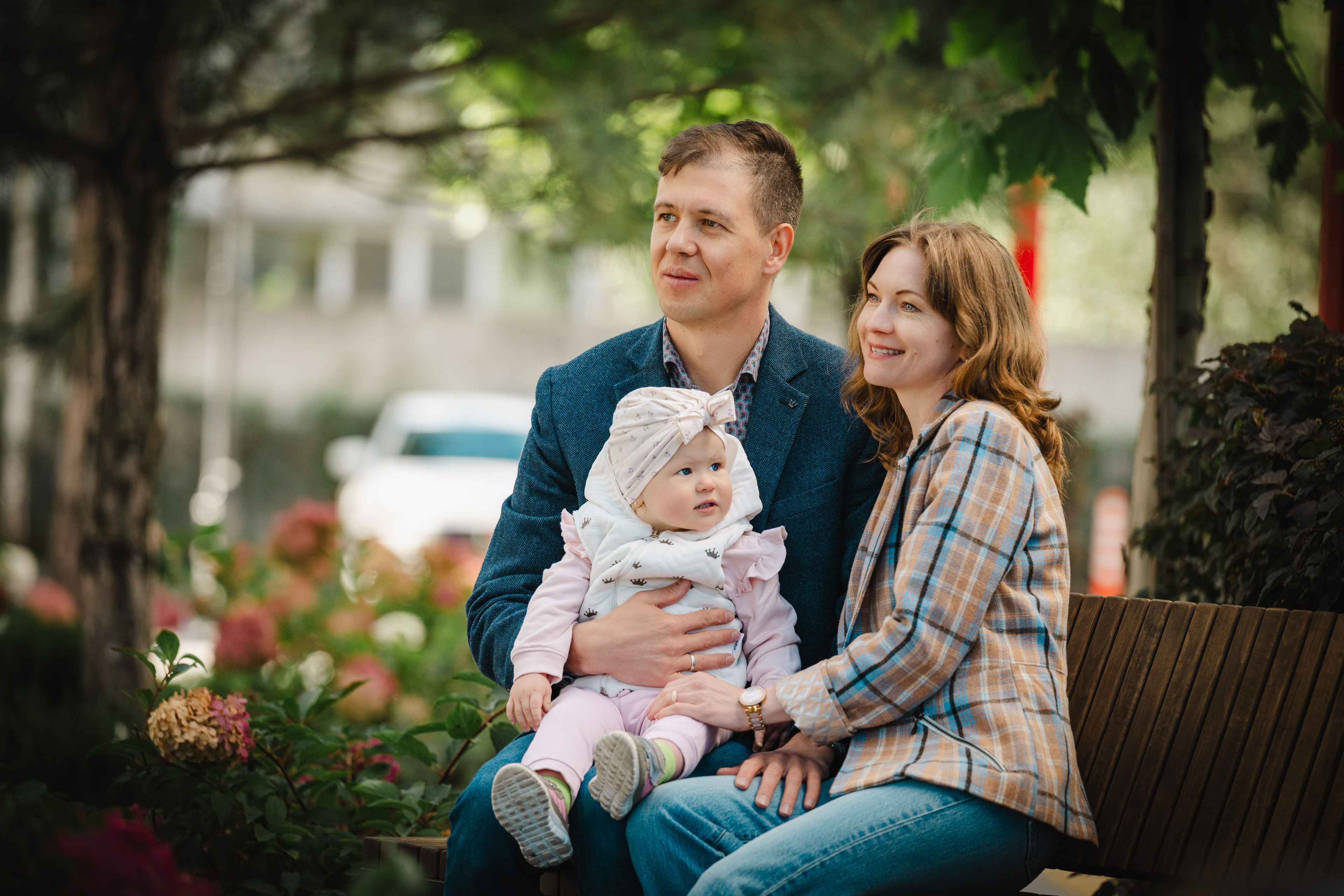 На фото жінка та чоловік з дитиною на руках на вулиці