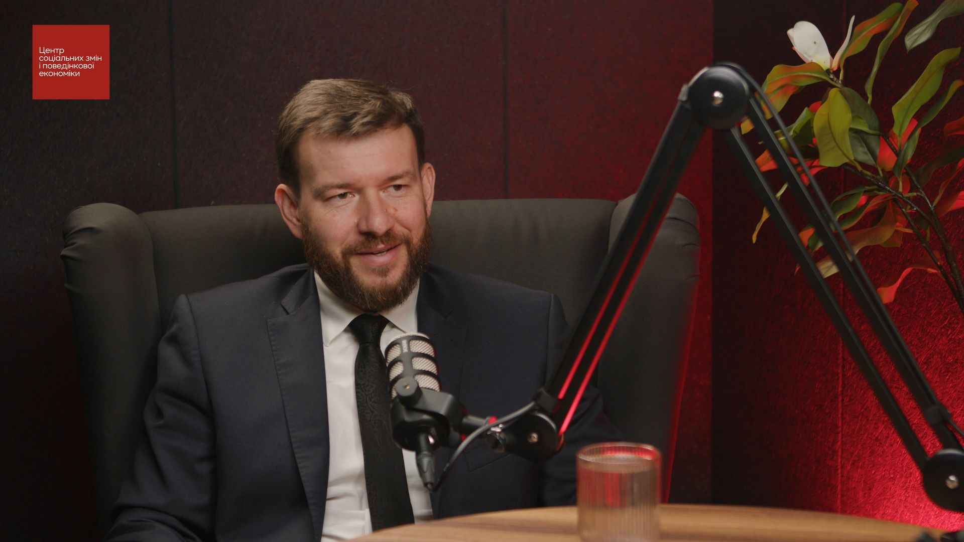 На фото чоловік сидить перед мікрофоном