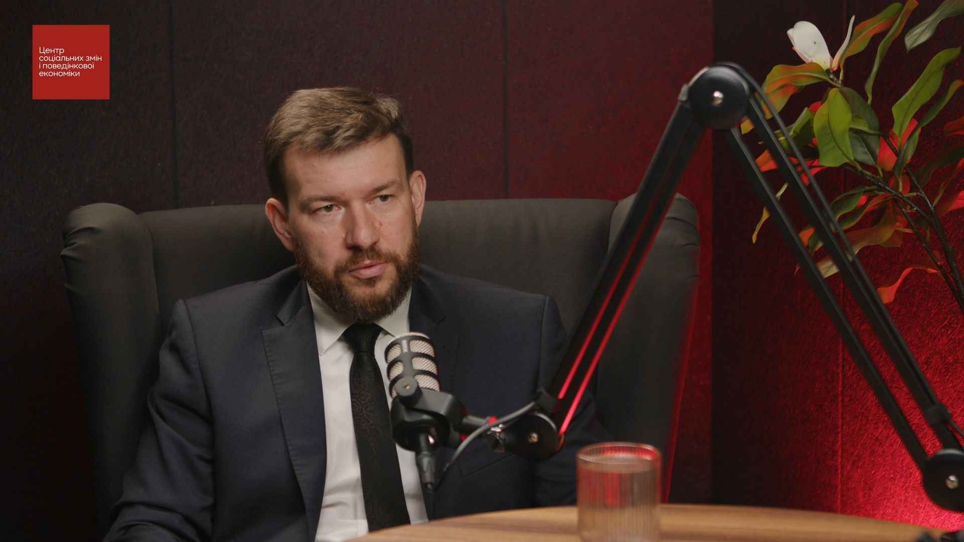 На фото чоловік сидить перед мікрофоном