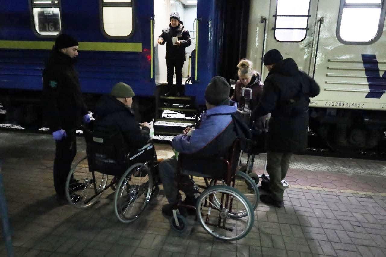 Дві людини на візку на фоні поїзду