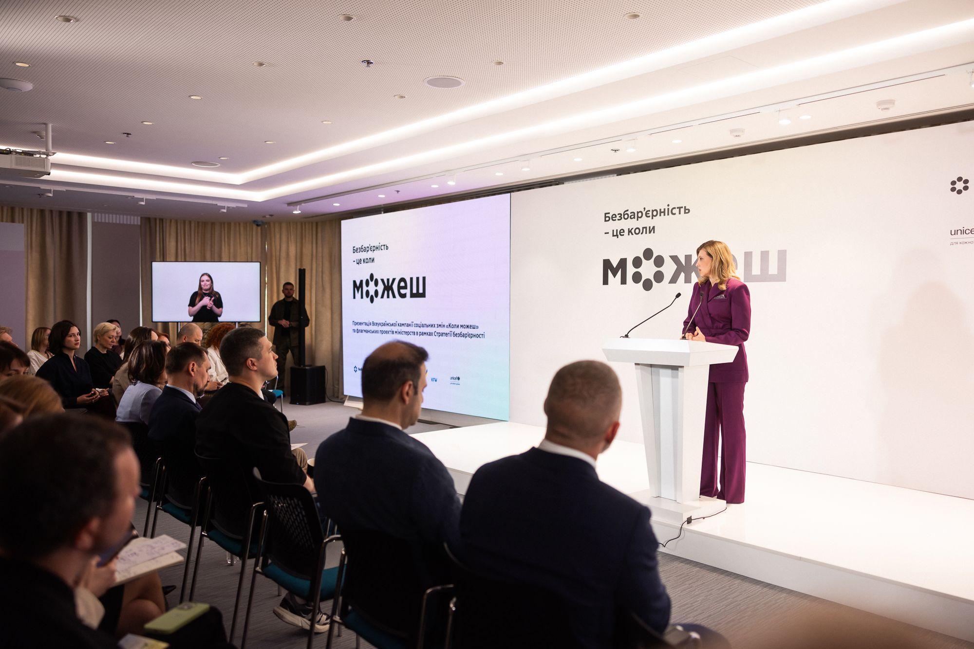 На фото Олена Зеленська виступає на фоні сцени