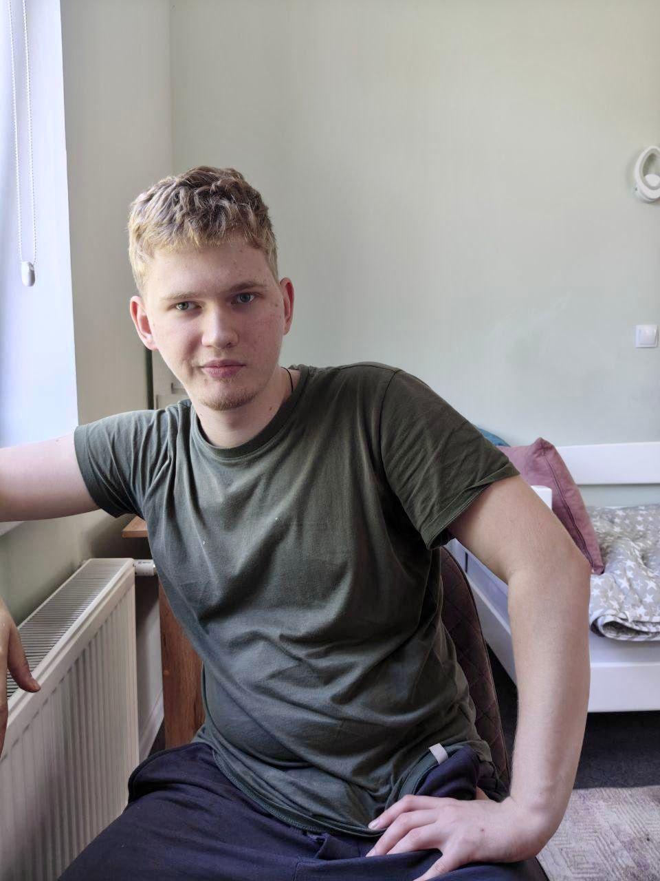 На фото хлопець сидить на стільці