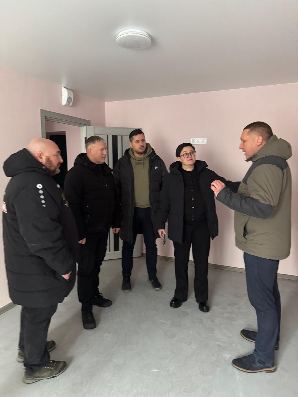 На фото чоловіки та жінка спілку.ться у приміщенні