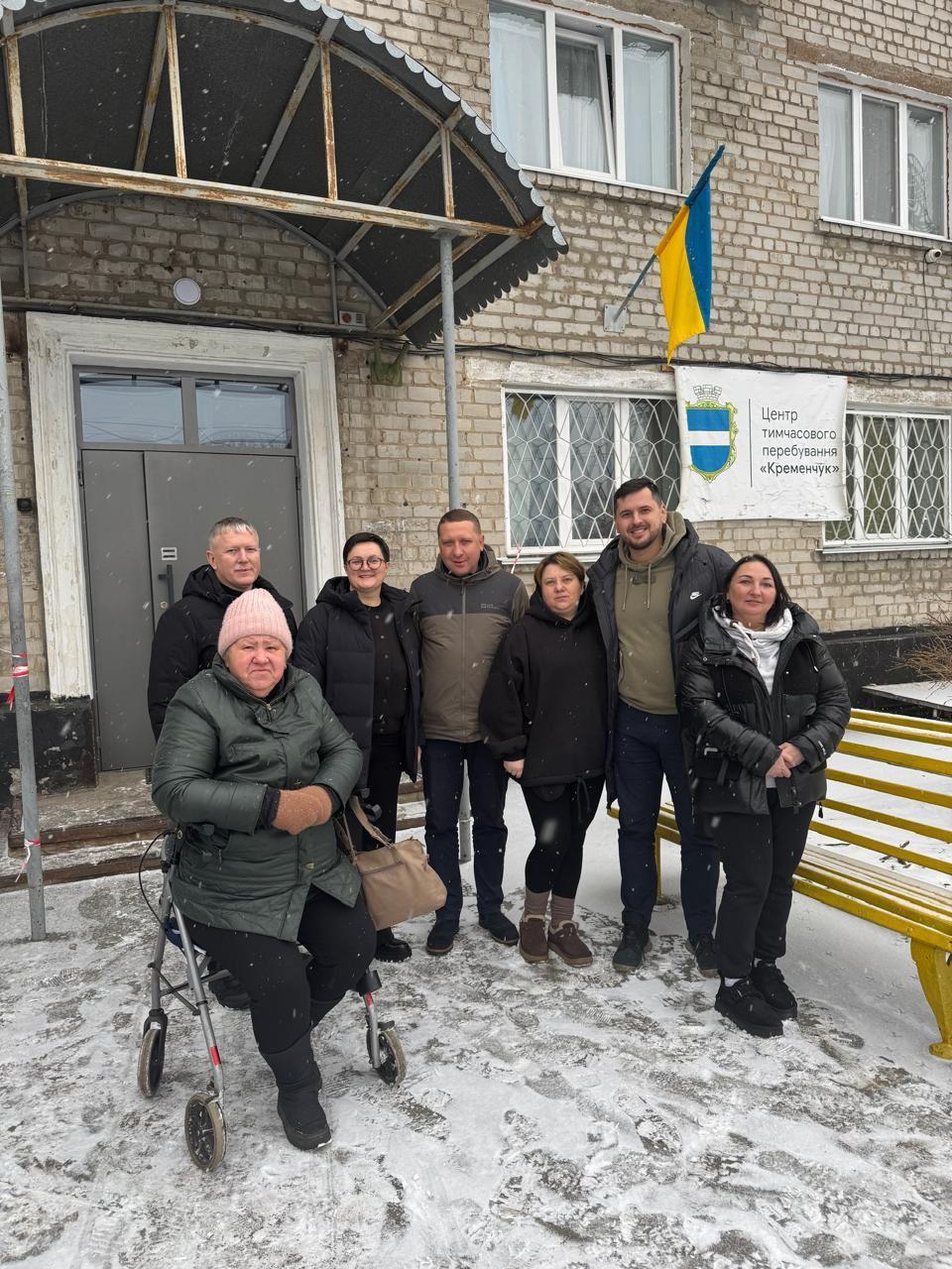 На фото жінки та чоловіки стоять на вулиці на фоні приміщення