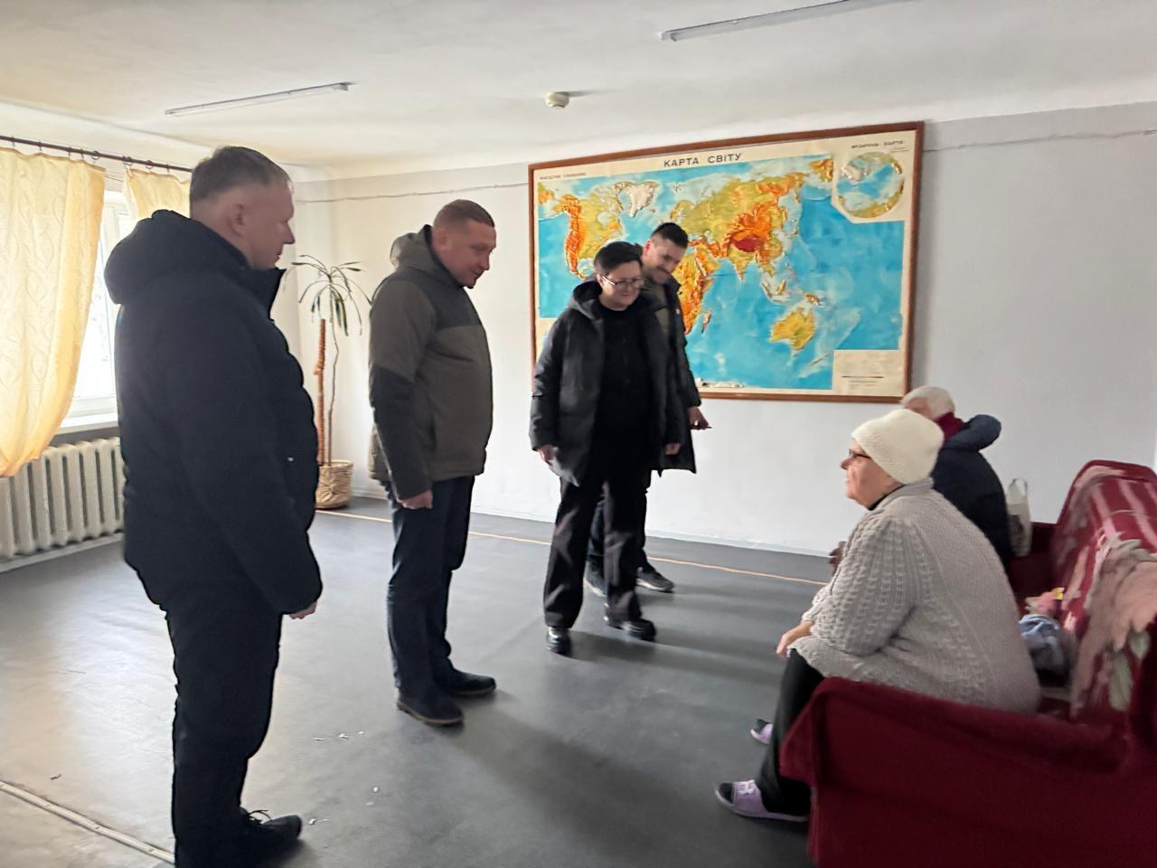 На фото чоловіки та жінка спілкуються з жінками у приміщенні