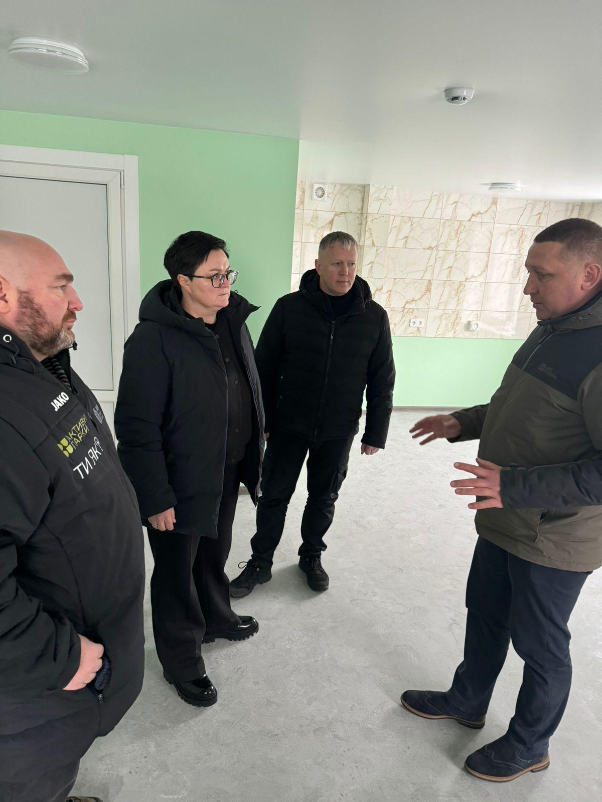 На фото чоловіки та жінка спілкуються у приміщенні