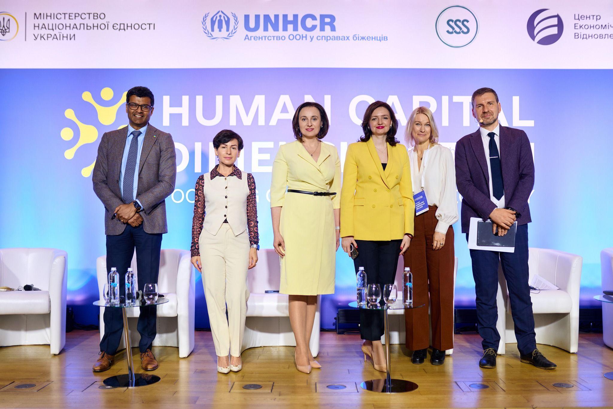 На фото чоловіки і жінки стоять на фоні сцени