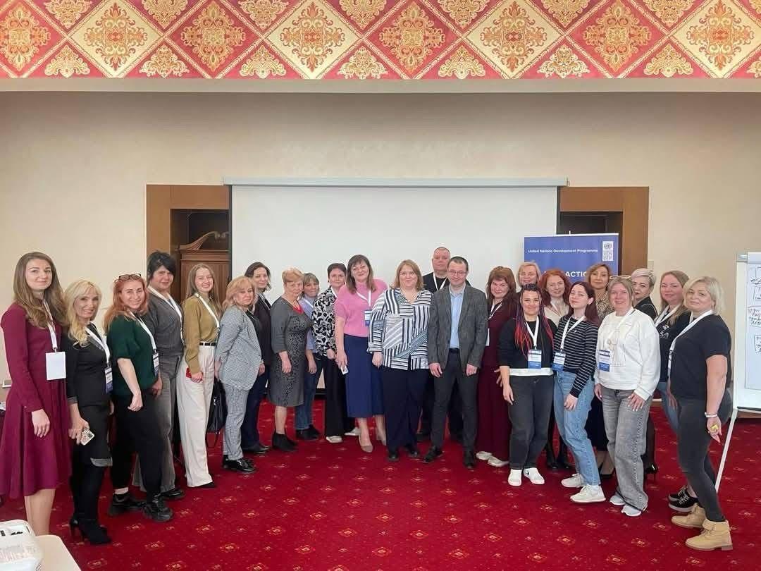 Жінки та чоловік фотографуються на фоні стіни