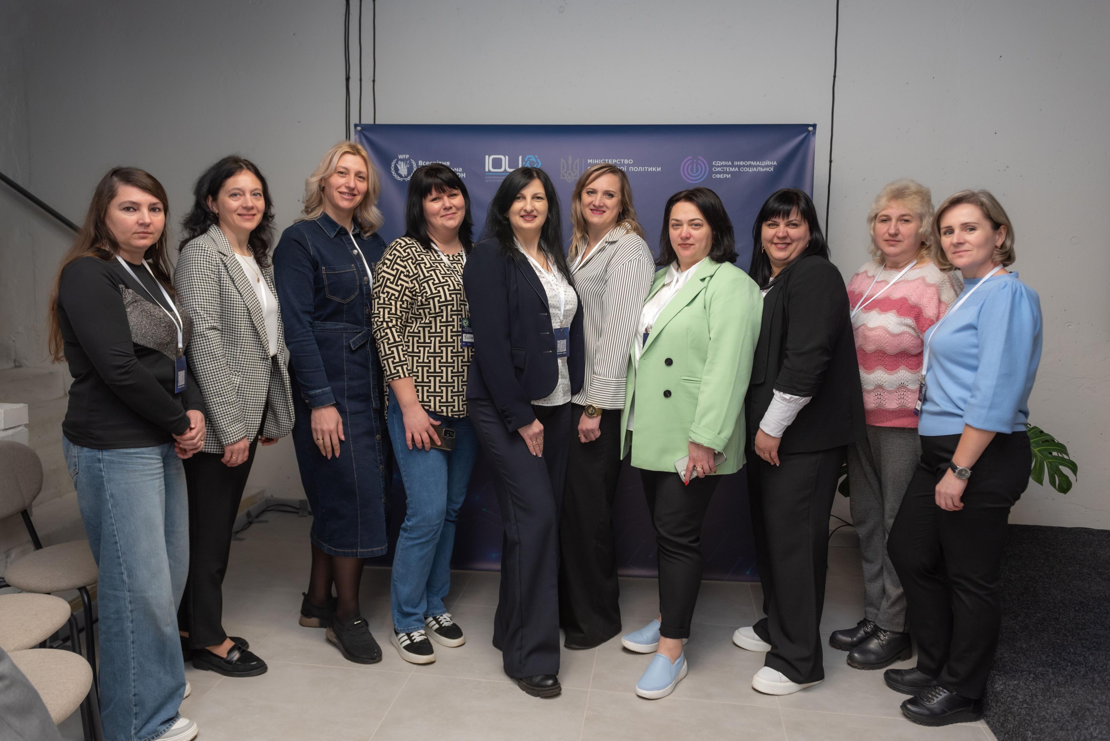 Учасниці семінару «ЄІССС: оптимізація роботи та нові можливості» стоять на фоні банеру