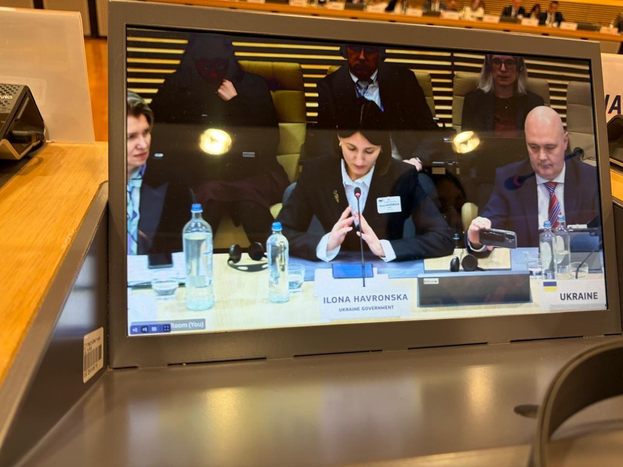 На фото чоловіки та жінка під час заходу сидять за столом