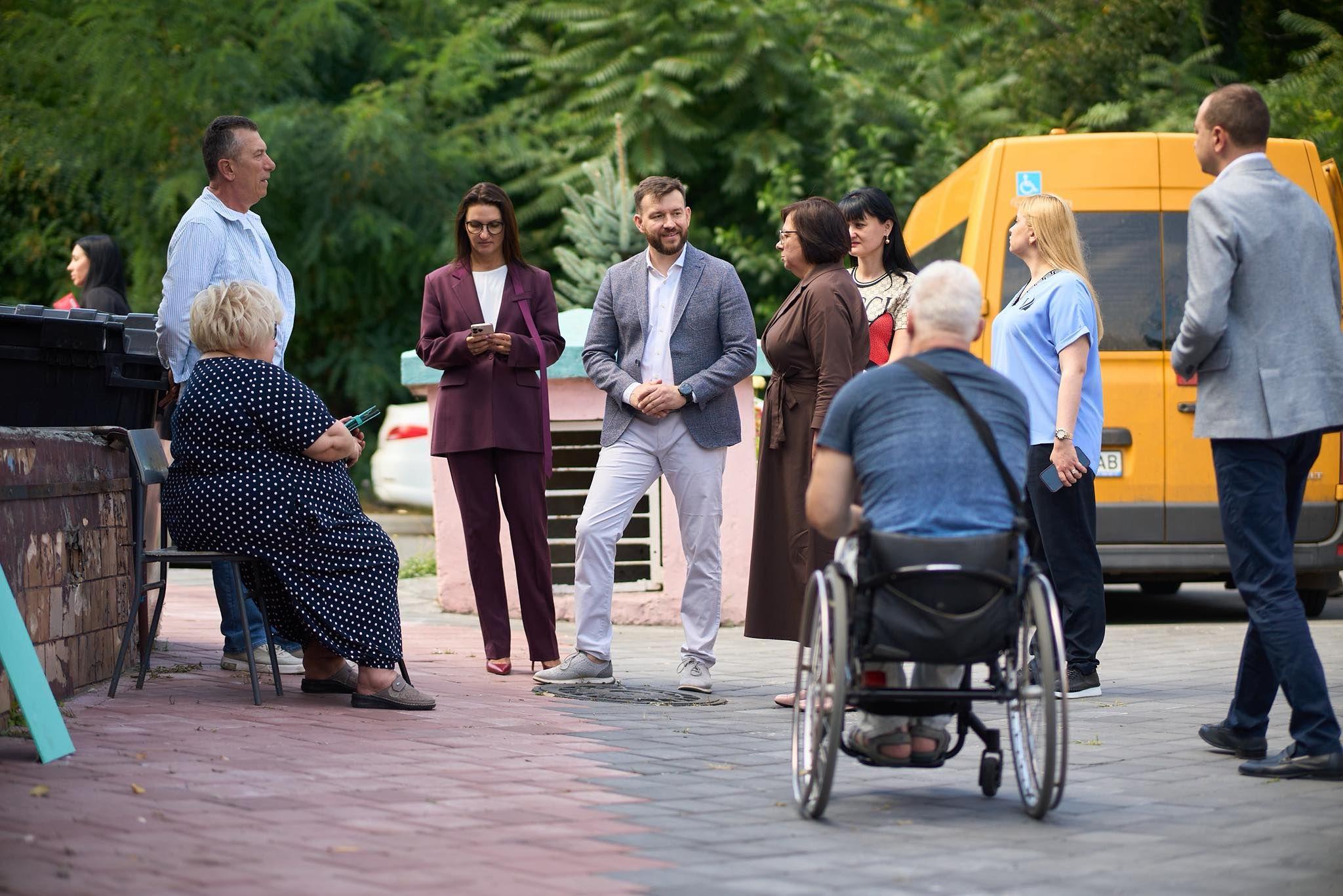 На фото чоловік та жінки спілкуються з людьми на вулиці