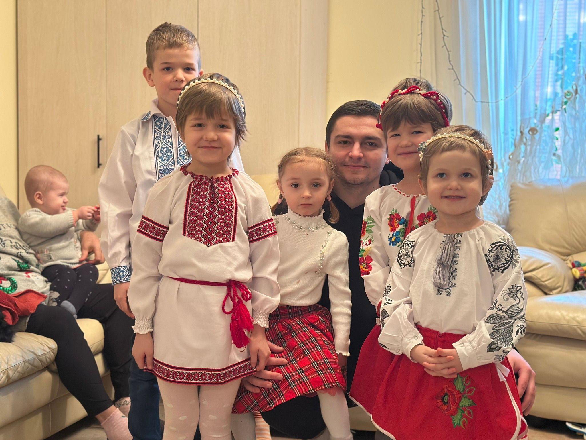 На фото чоловік та діти у вишиванках у кімнаті