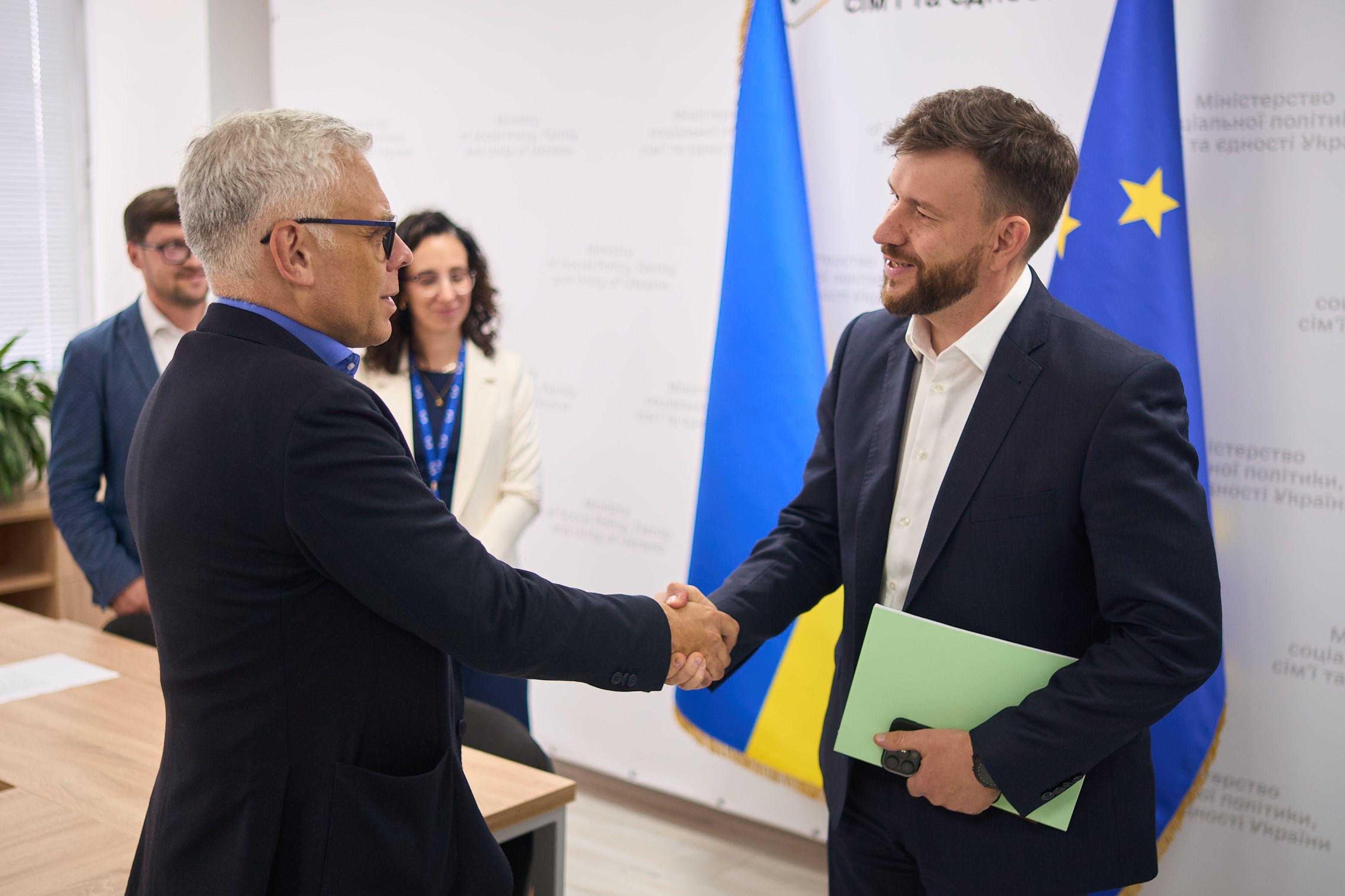 На фото двоє чоловіків вітаються за руку