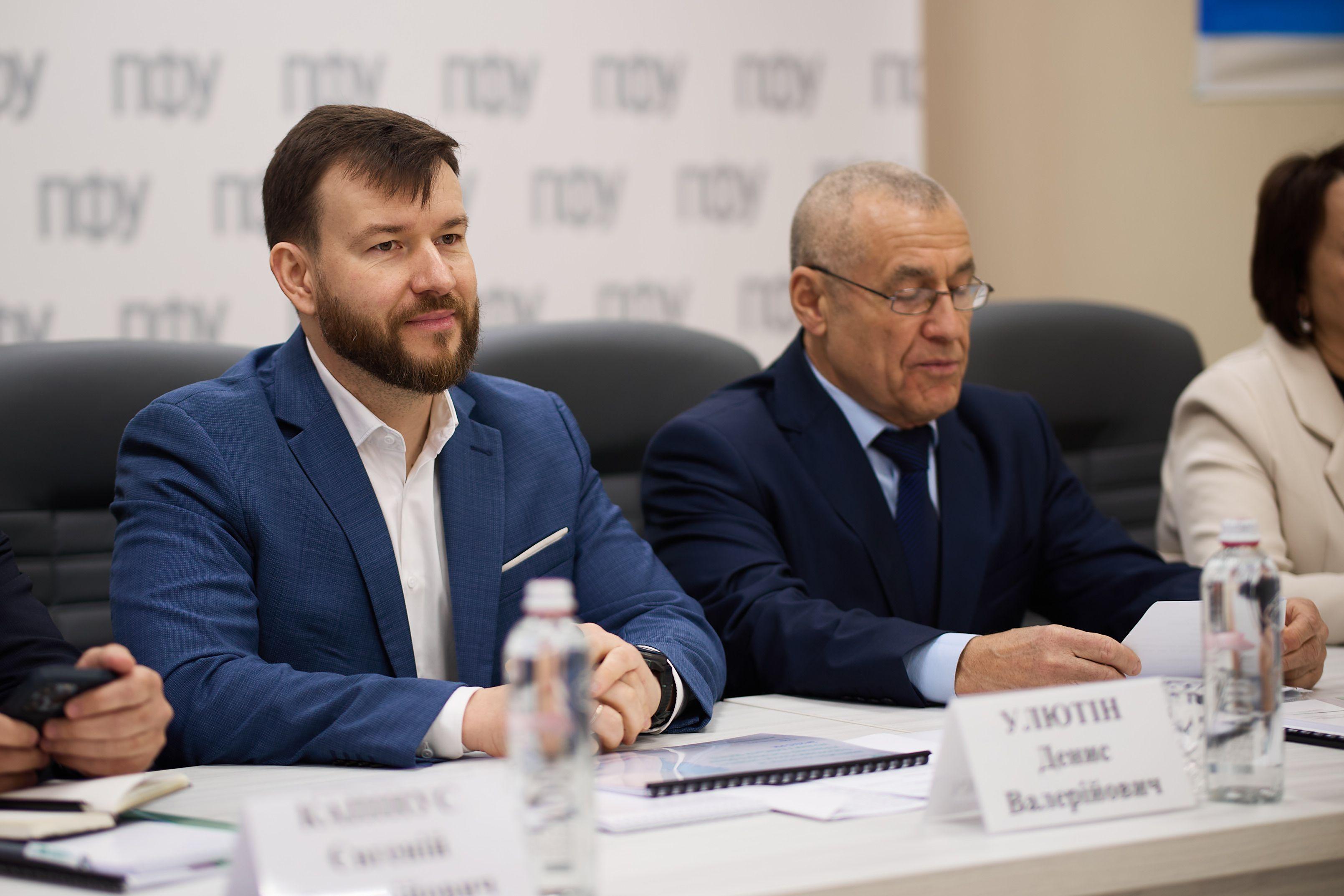 На фото чоловіки сидять за столом під час заходу