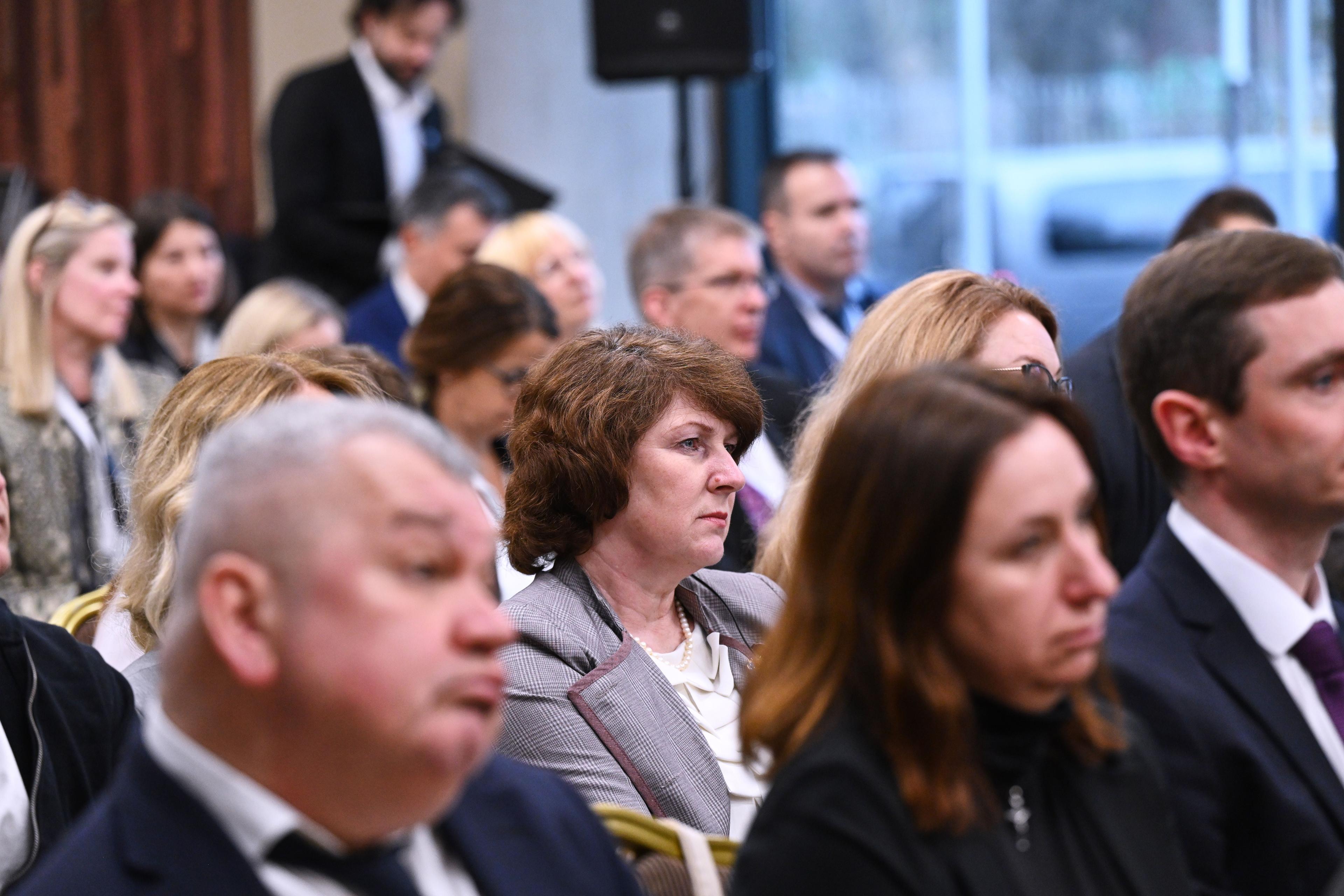 На фото чоловіки та жінки сидять в залі під час заходу
