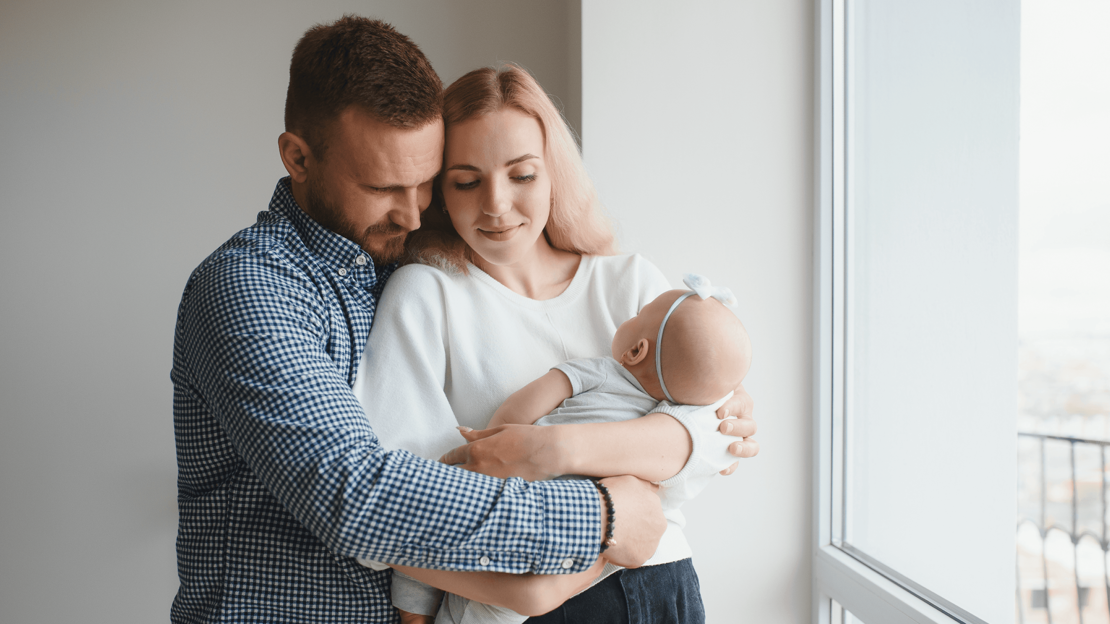 На фото чоловік обнімає жінку, яка тримає на руках немовля