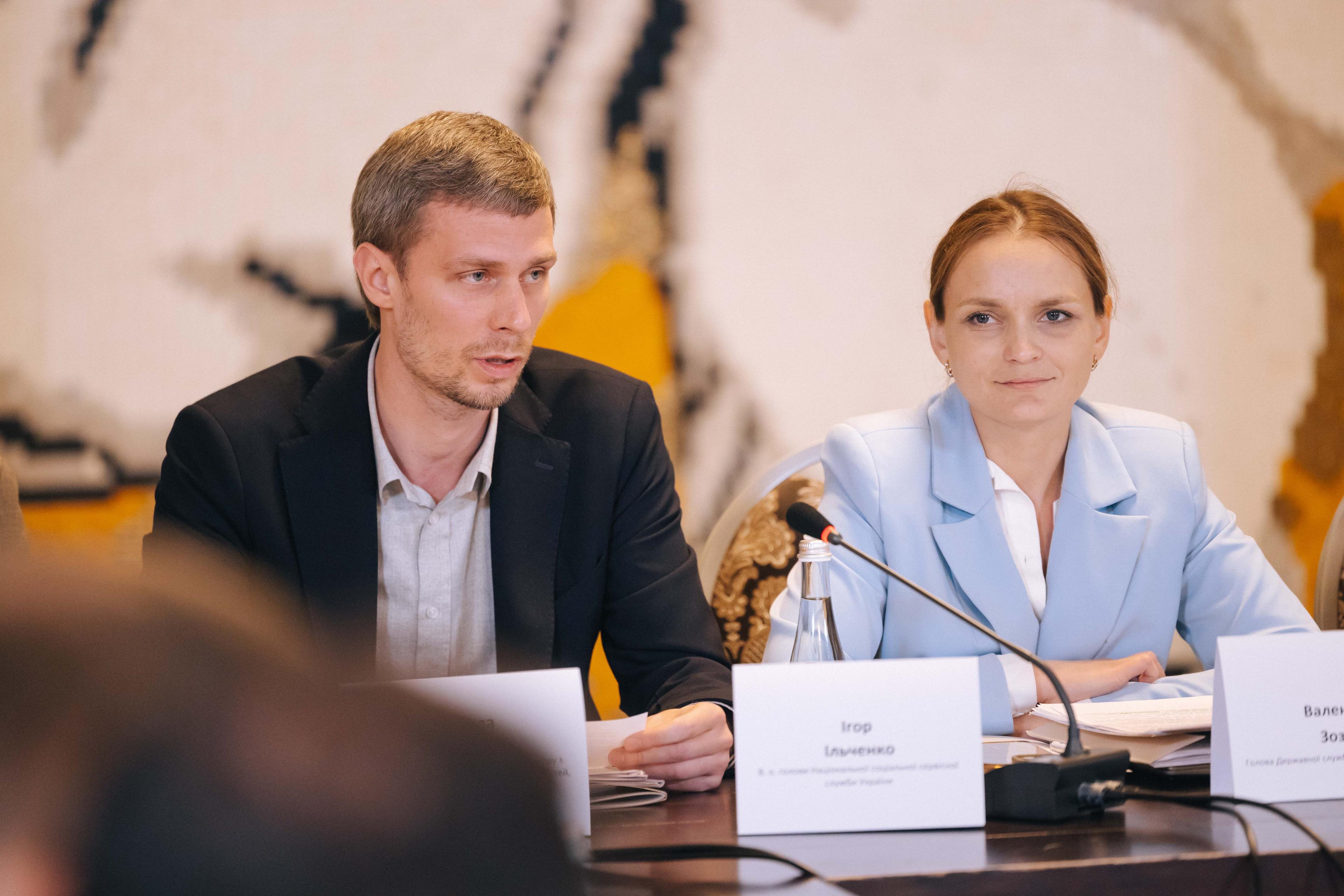 На фото чоловіки і жінка сидять за столом під час заходу