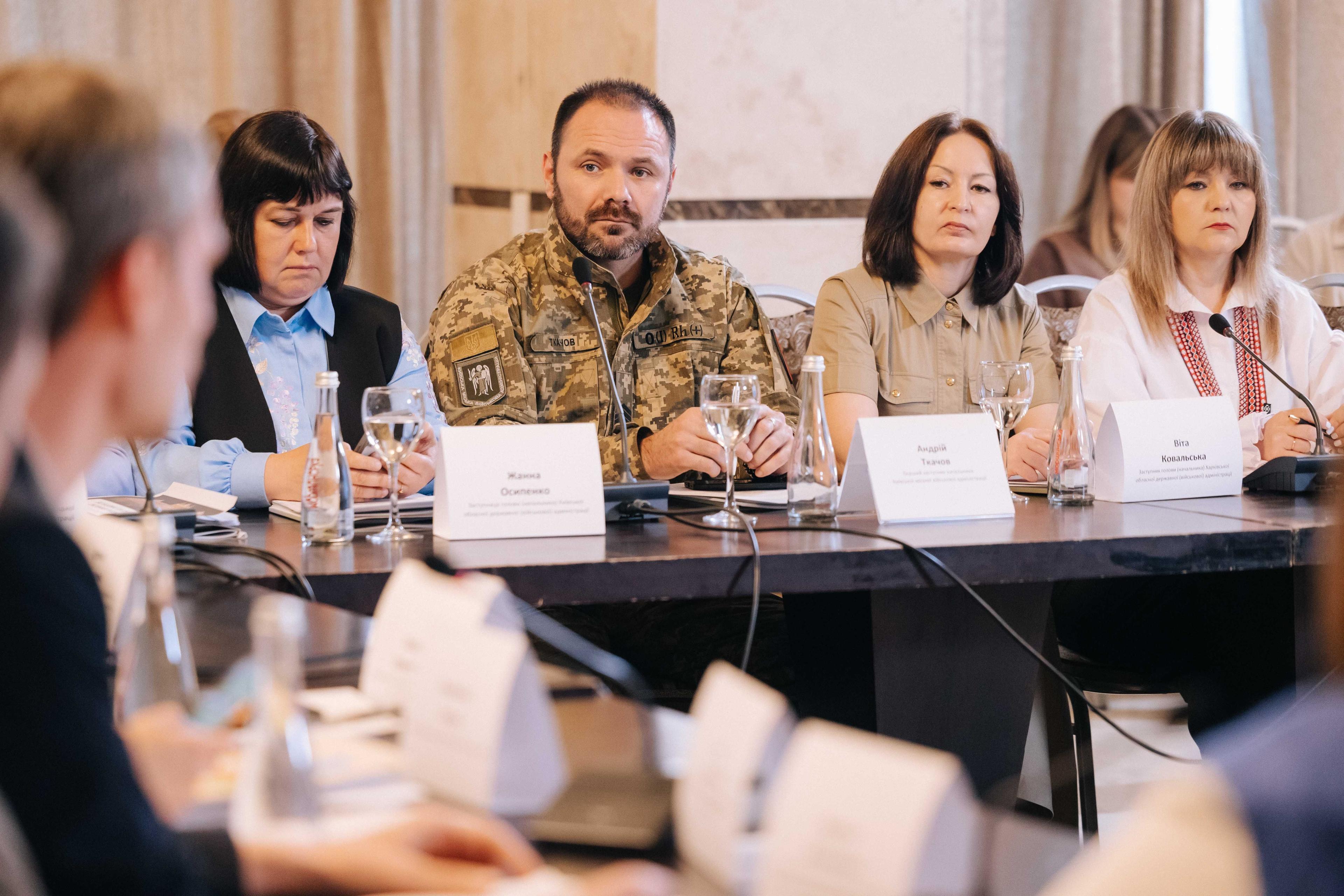 На фото жінки та чоловіки сидять за столом під час заходу