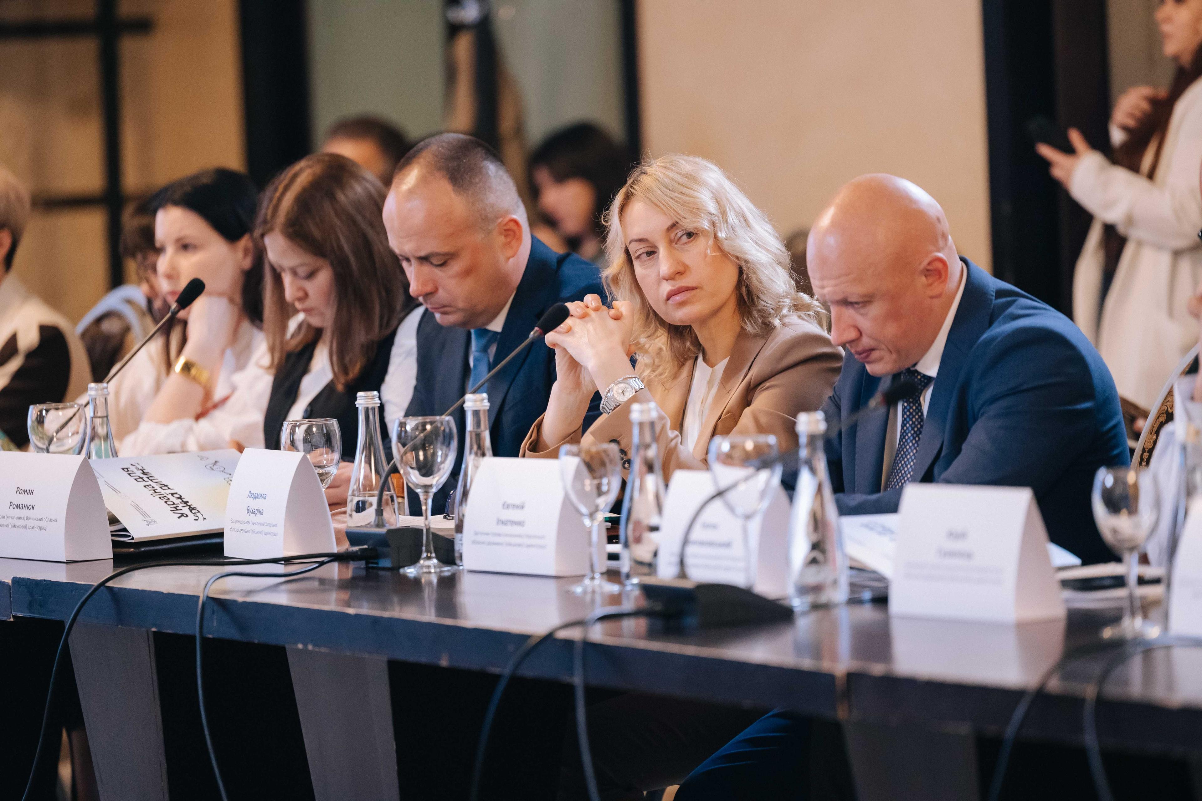 На фото жінки та чоловіки сидять за столом під час заходу