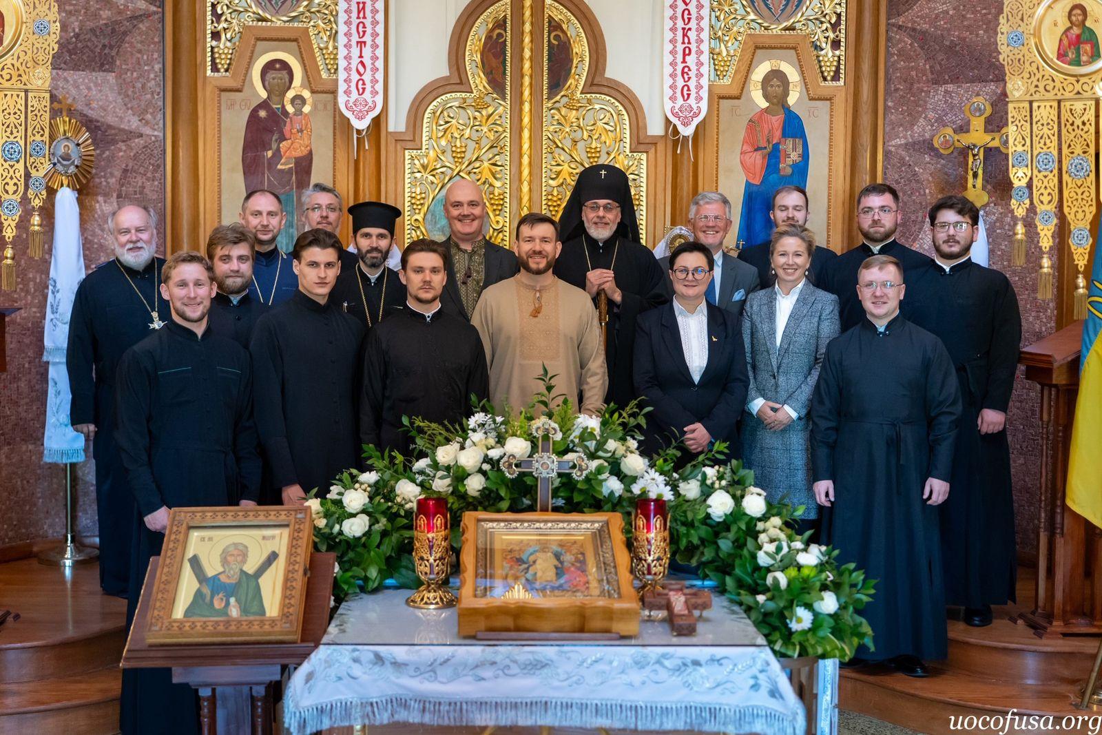 На фото чоловіки та жінка стоять у приміщенні церкви