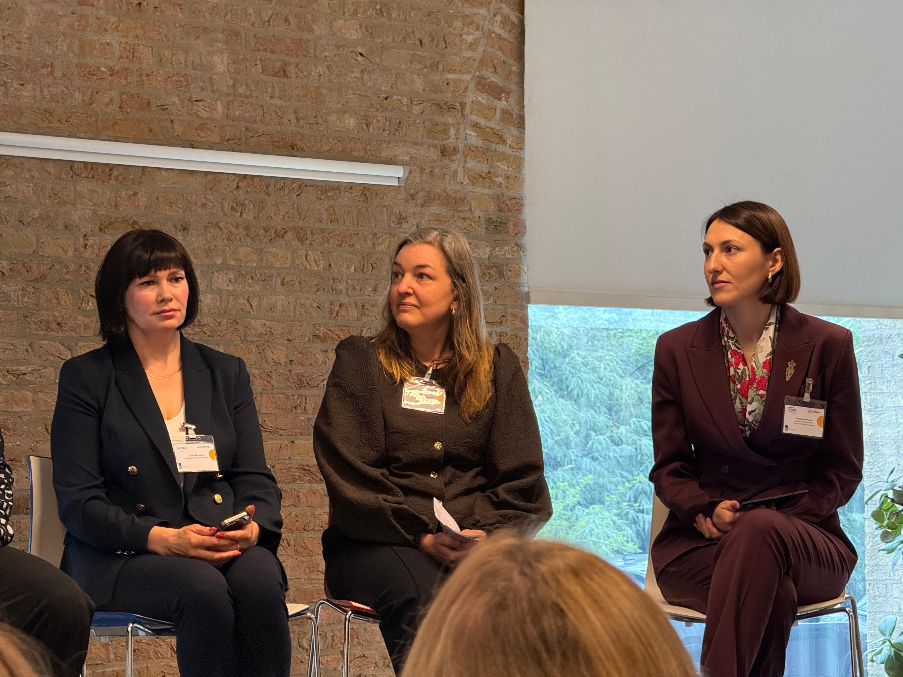 На фото жінки сидять на сцені під час заходу