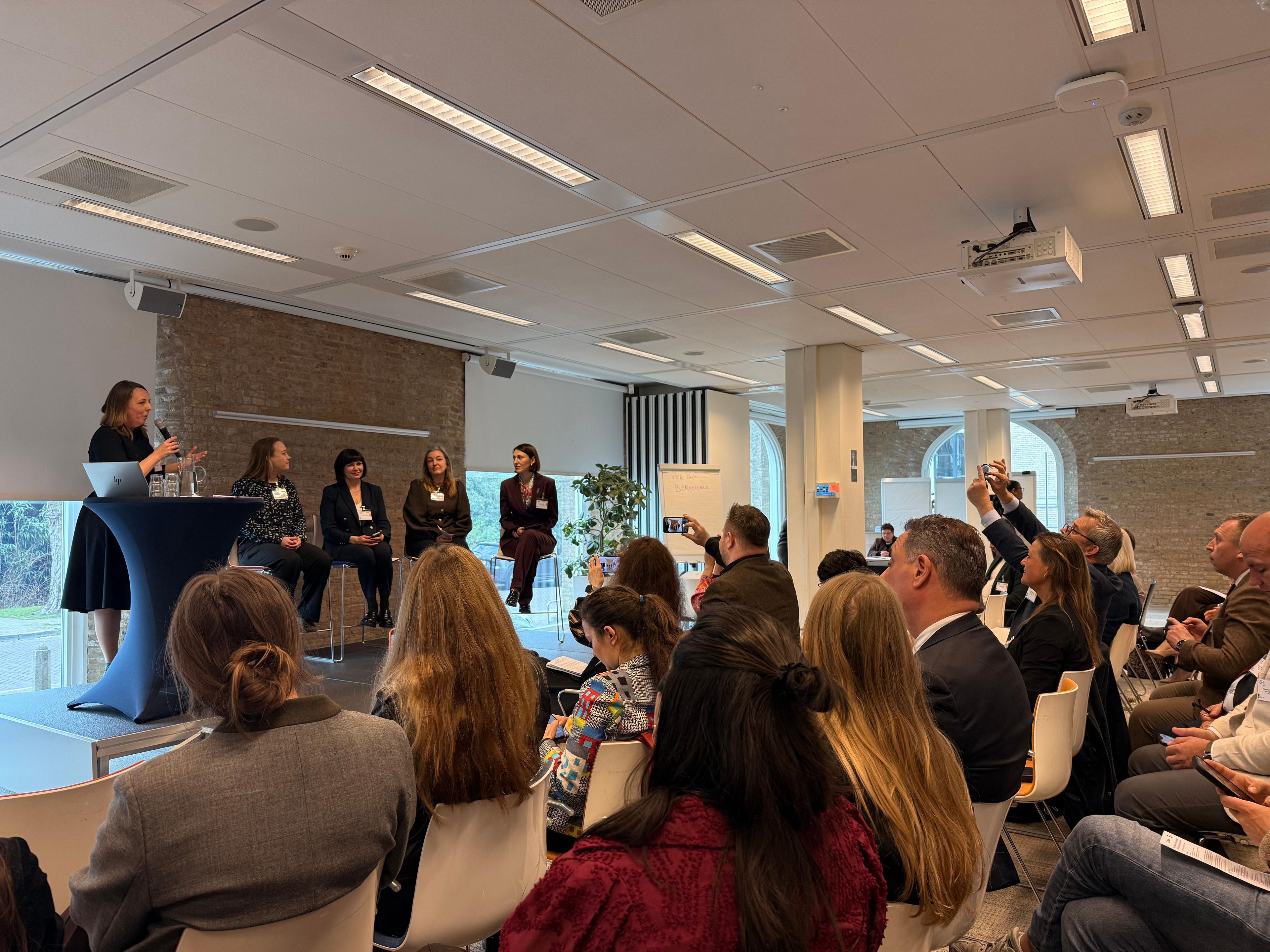 На фото жінки та чоловіки сидять в залі під час заходу