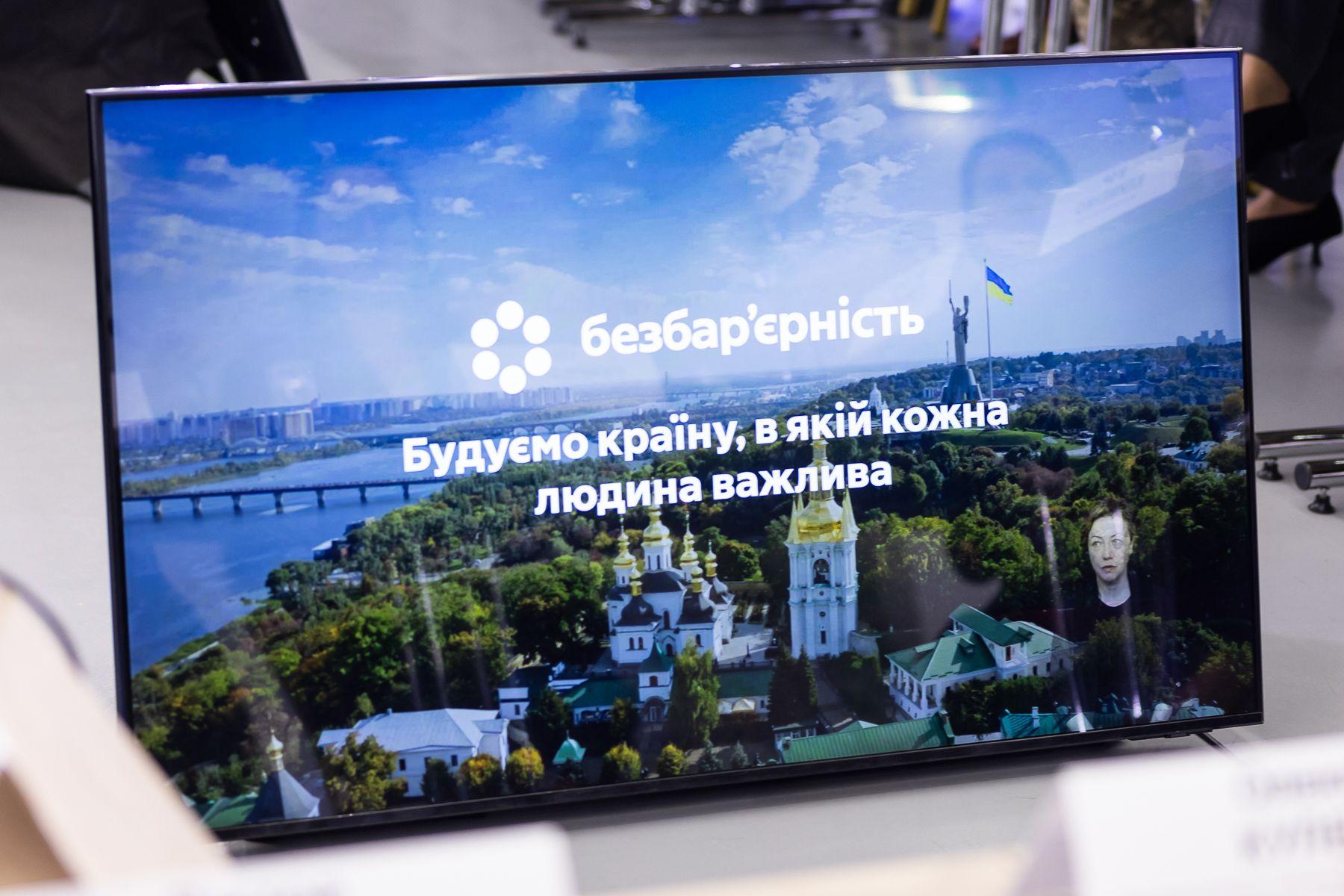 На екрані зображено Київ із видом на Дніпро, Києво-Печерську Лавру та монумент «Батьківщина-Мати». Текст українською мовою говорить:  Безбар'єрність Будуємо країну, в якій кожна людина важлива