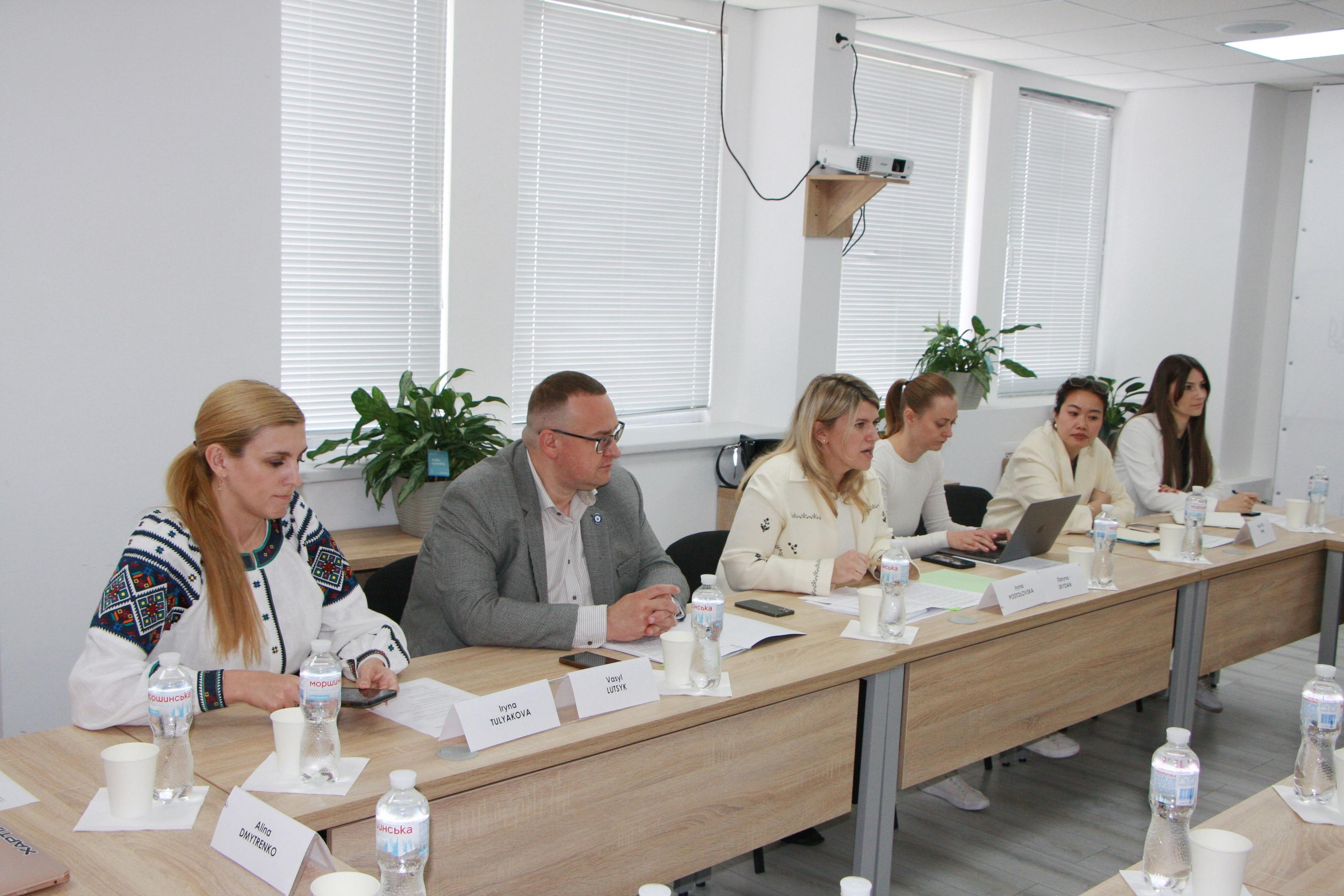На фото жінки та чоловік сидять за столом під час зустрічі