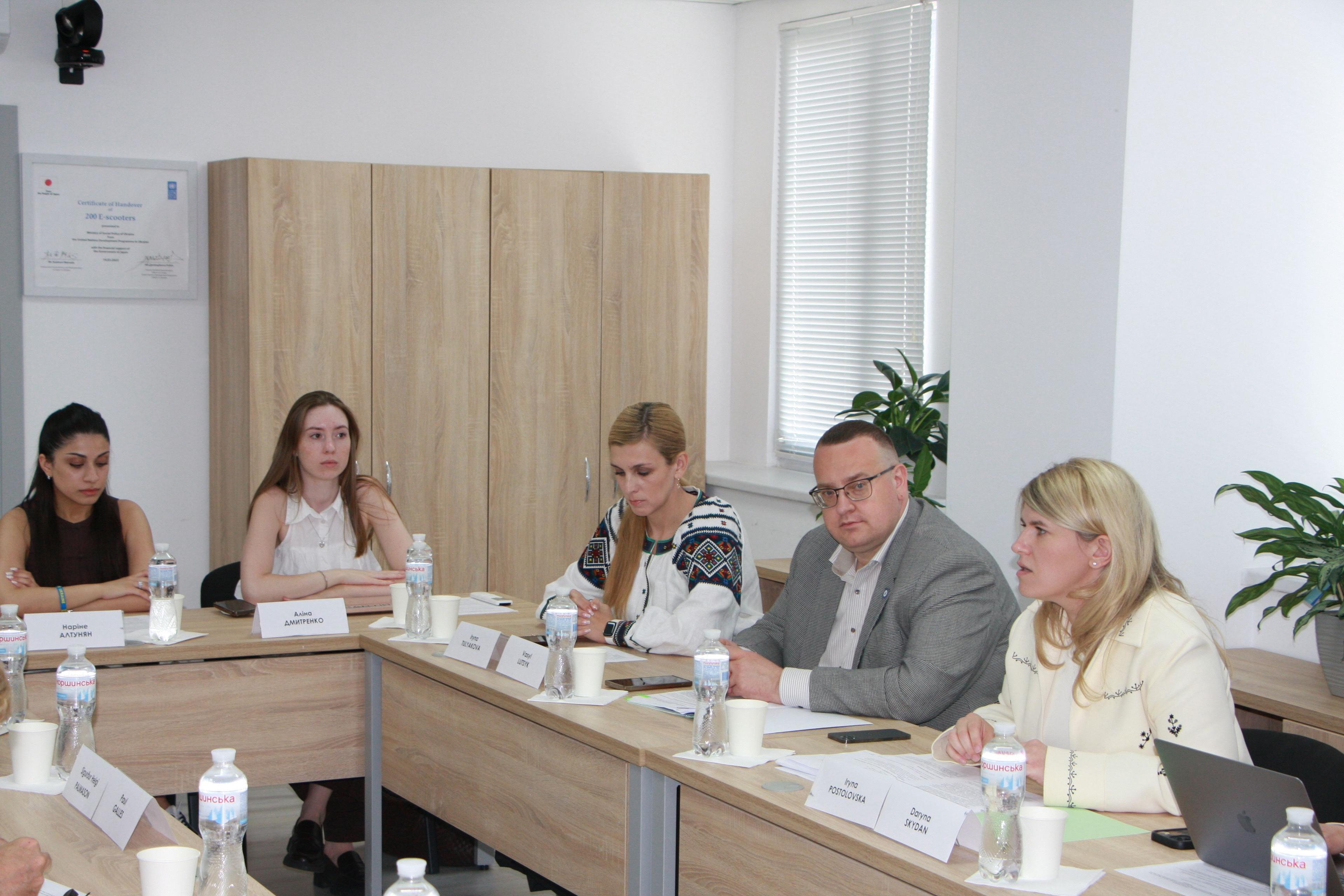 На фото жінки та чоловік сидять за столом