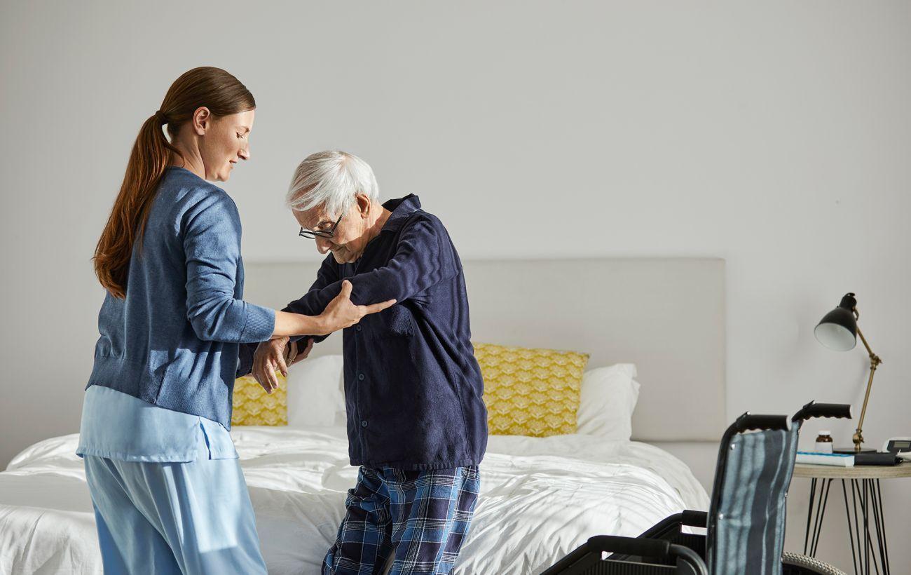 На фото жінка тримає за руку особу похилого віку