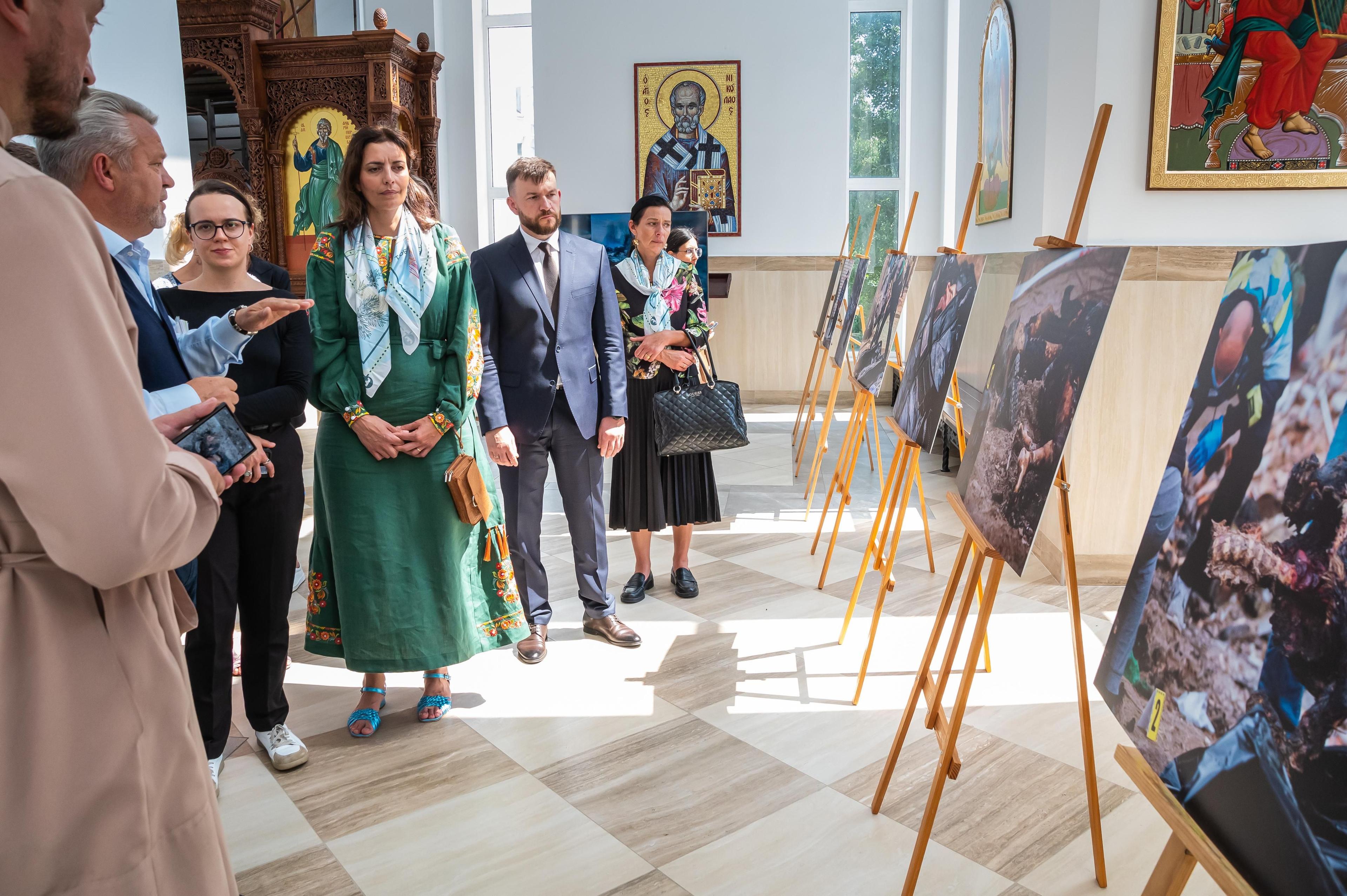 На фото чоловіки та жінки оглядають картини